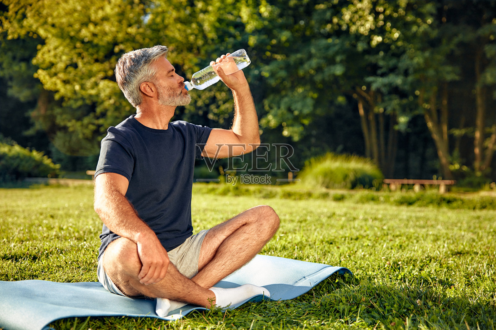 一个放松的男人在大自然中享受正念练习，同时带着水瓶。照片摄影图片