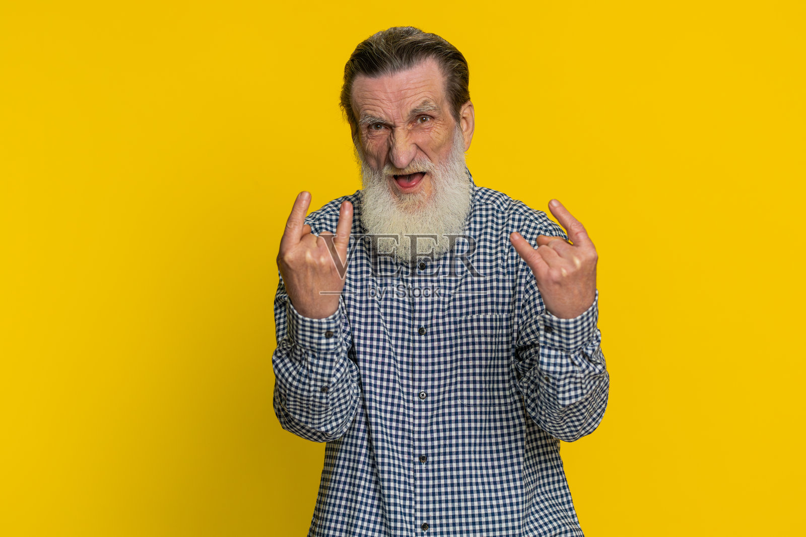 快乐的老年人用手做出摇滚手势，表情夸张，正在跳舞庆祝胜利。照片摄影图片