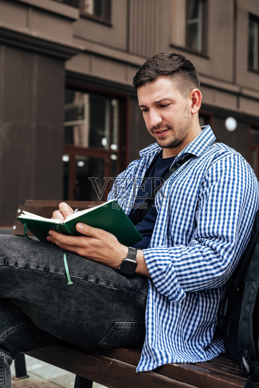一个人坐在公园长椅上写笔记本。照片摄影图片