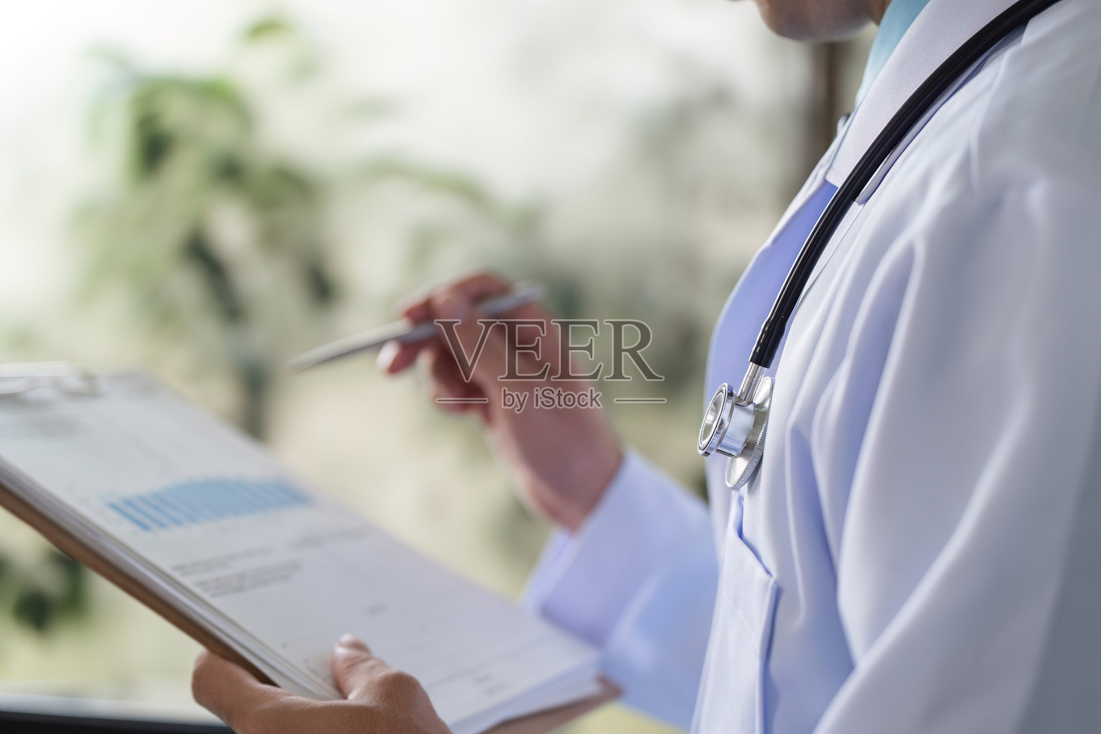 男性医生在现代医疗办公室环境中查看病人名单夹。照片摄影图片