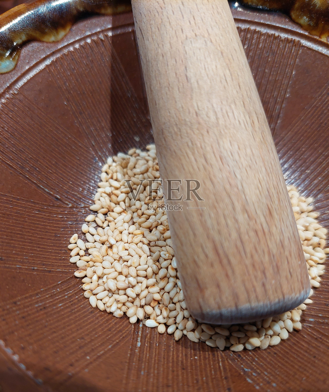 一个芝麻种子的碗和一个木棒用于研磨照片摄影图片