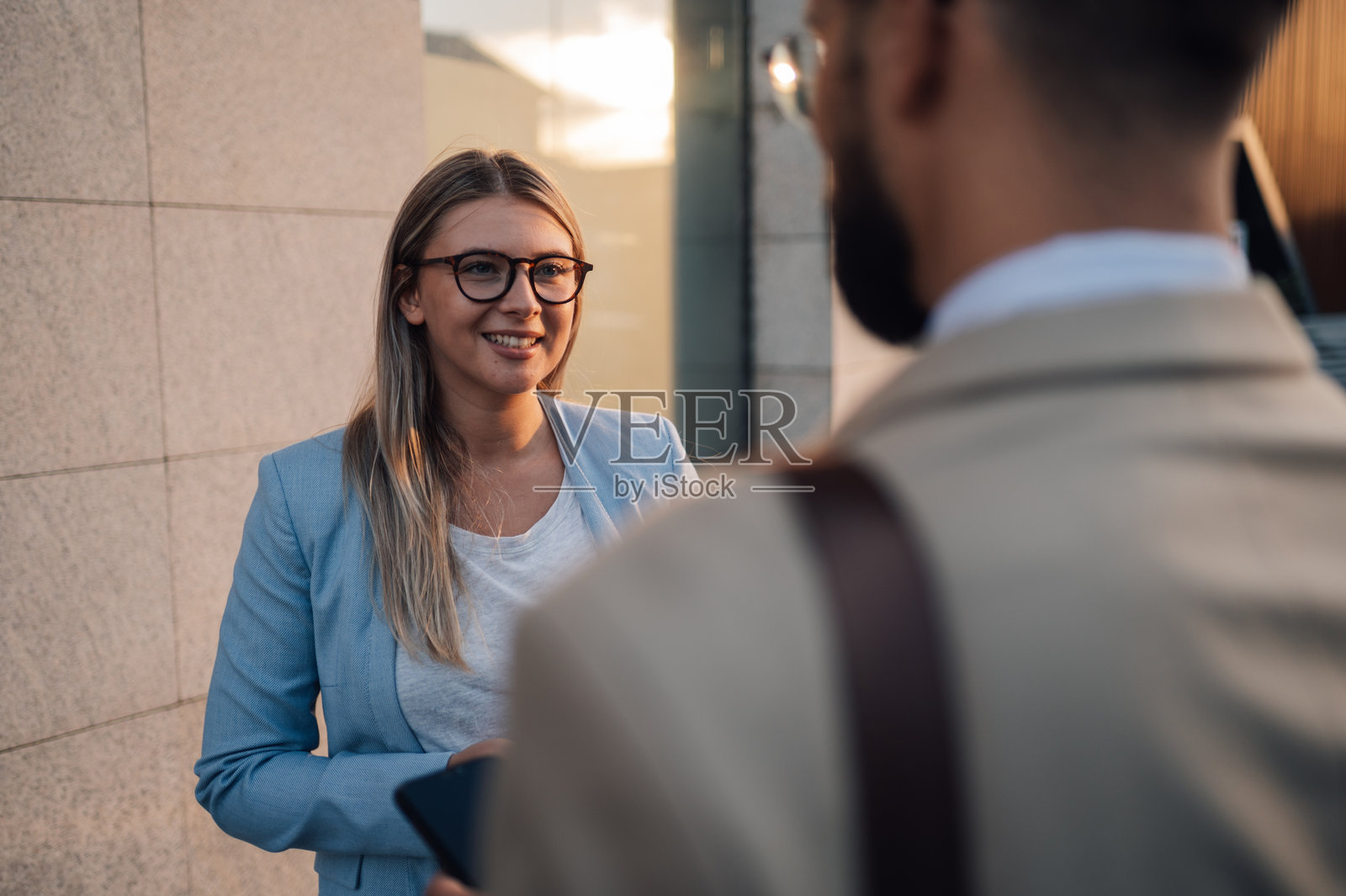 女商人在办公楼外与男商人交谈时微笑照片摄影图片