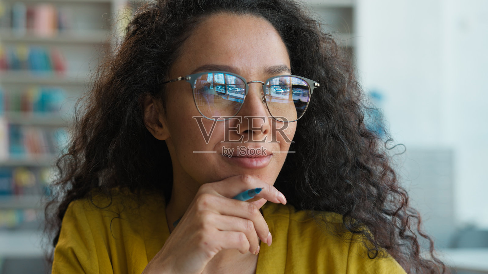 戴眼镜的拉丁裔白人西班牙裔女性，目光投向一旁，思考灵感，正在图书馆的笔记本上写作，学习作家、作者、记者的知识，毕业生，脑力认知，学术，大学，激励。照片摄影图片