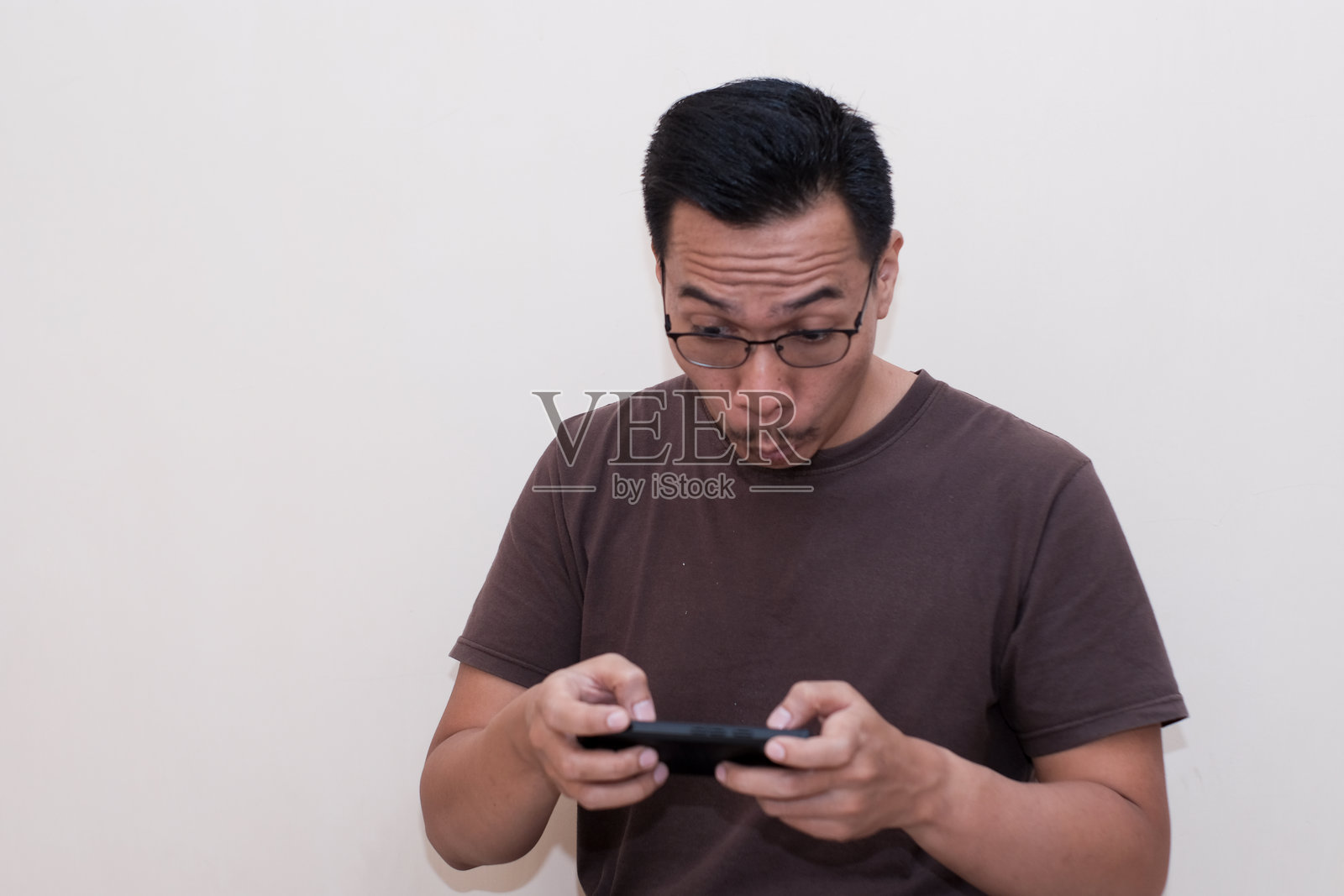 东南亚男子沉迷于手机游戏的疯狂搞笑表情照片摄影图片