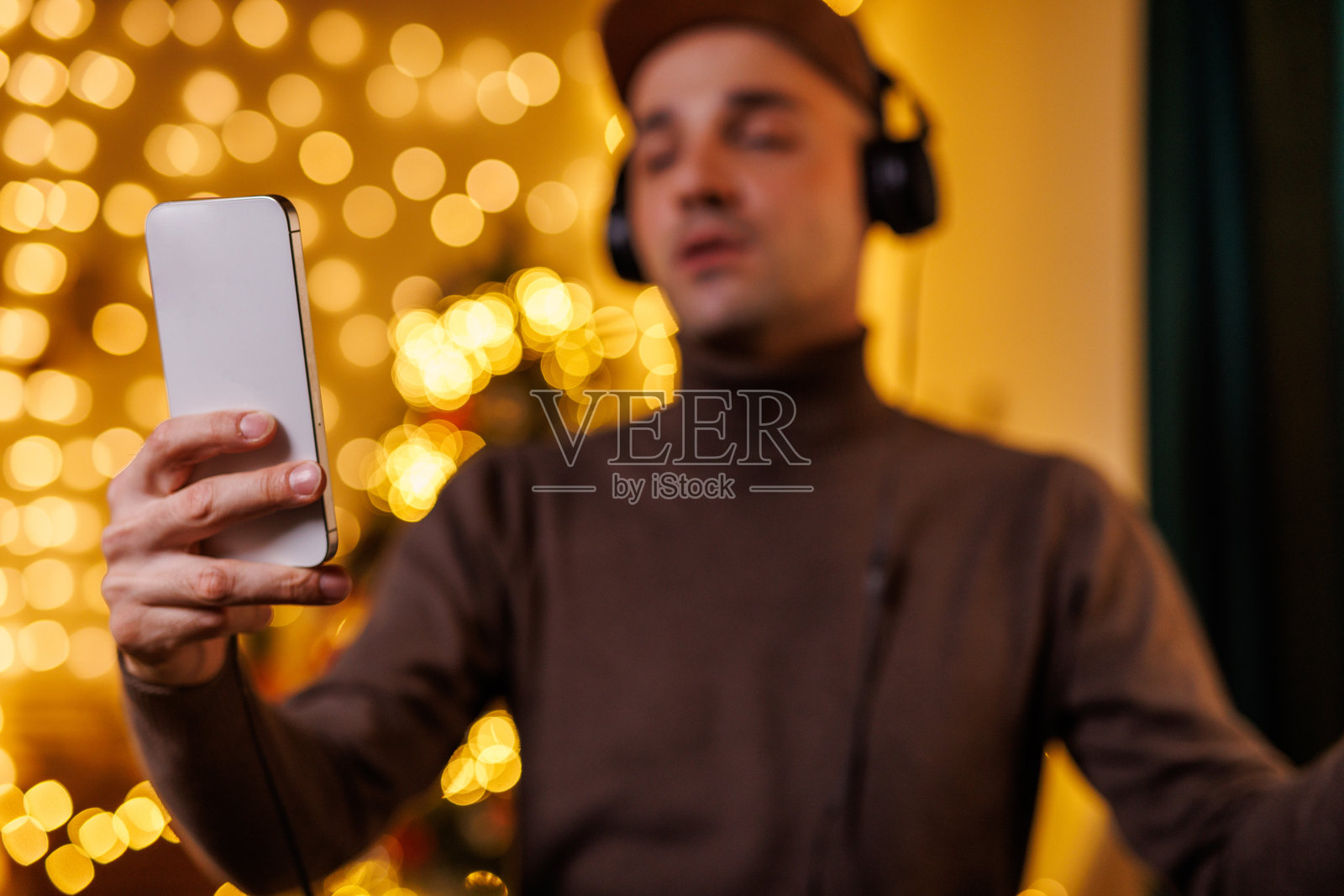 节日气氛中的男人在装饰一新的房间里戴着耳机打电话照片摄影图片