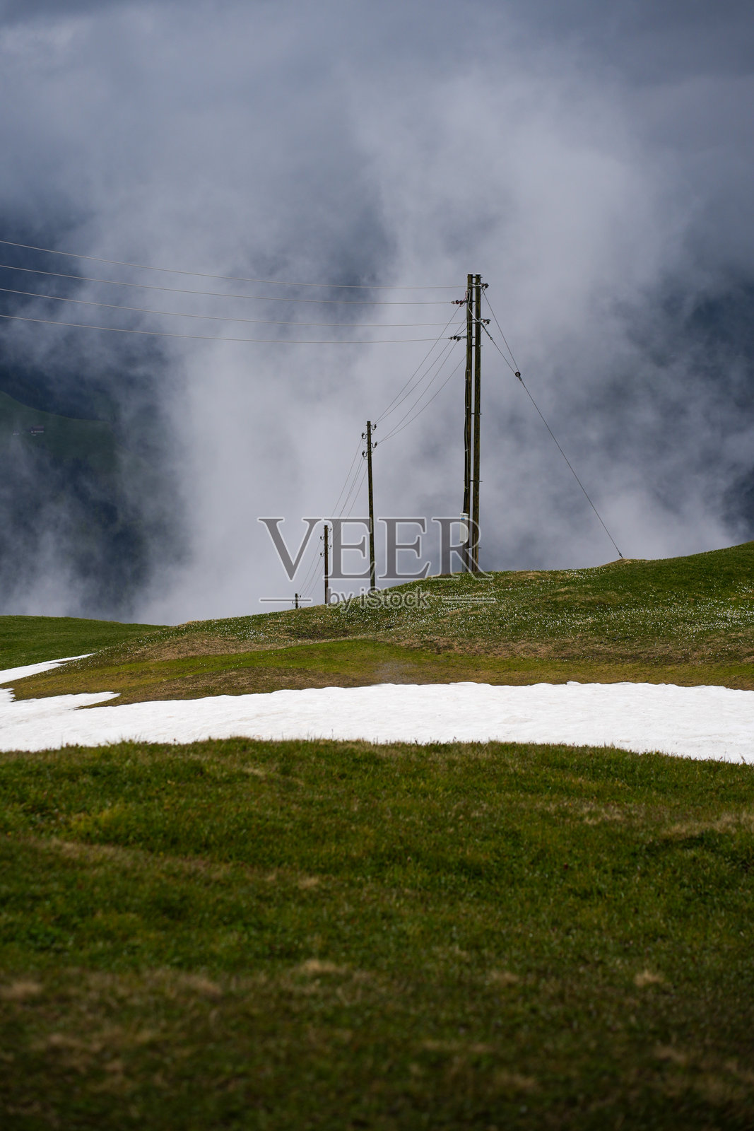 雾气弥漫的山坡上电力线与雪地斑块照片摄影图片