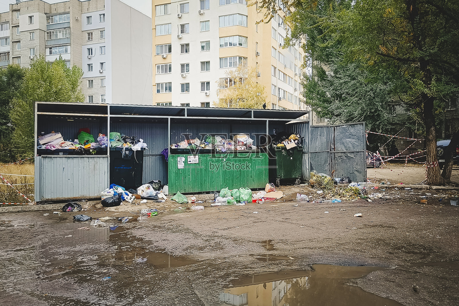 靠近一栋公寓楼的塑料垃圾桶装满了家庭垃圾。照片摄影图片