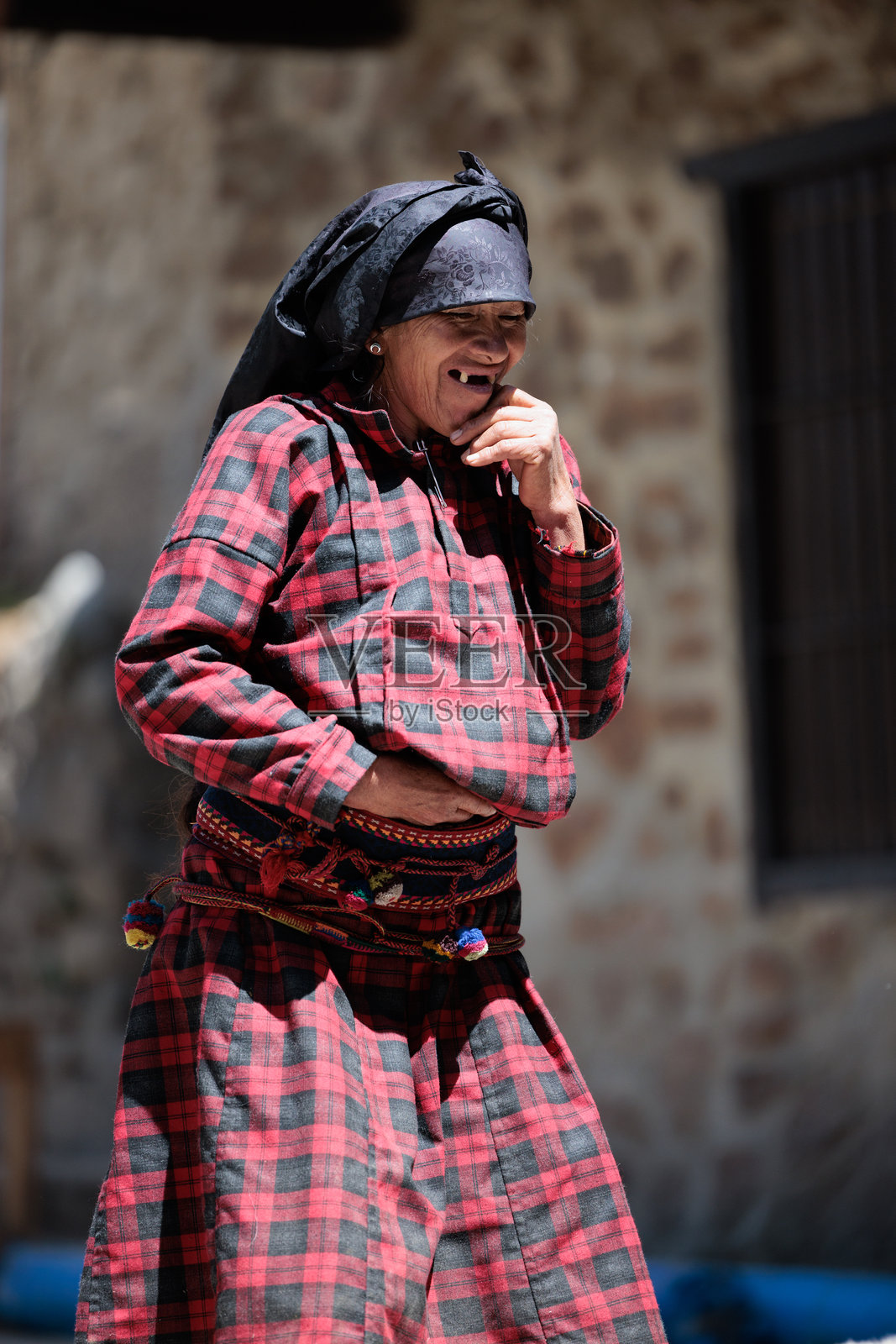 在美丽的秘鲁山脉中，捕捉到一位老年女性穿着传统服饰的场景，背景是图佩的风景街道。照片摄影图片