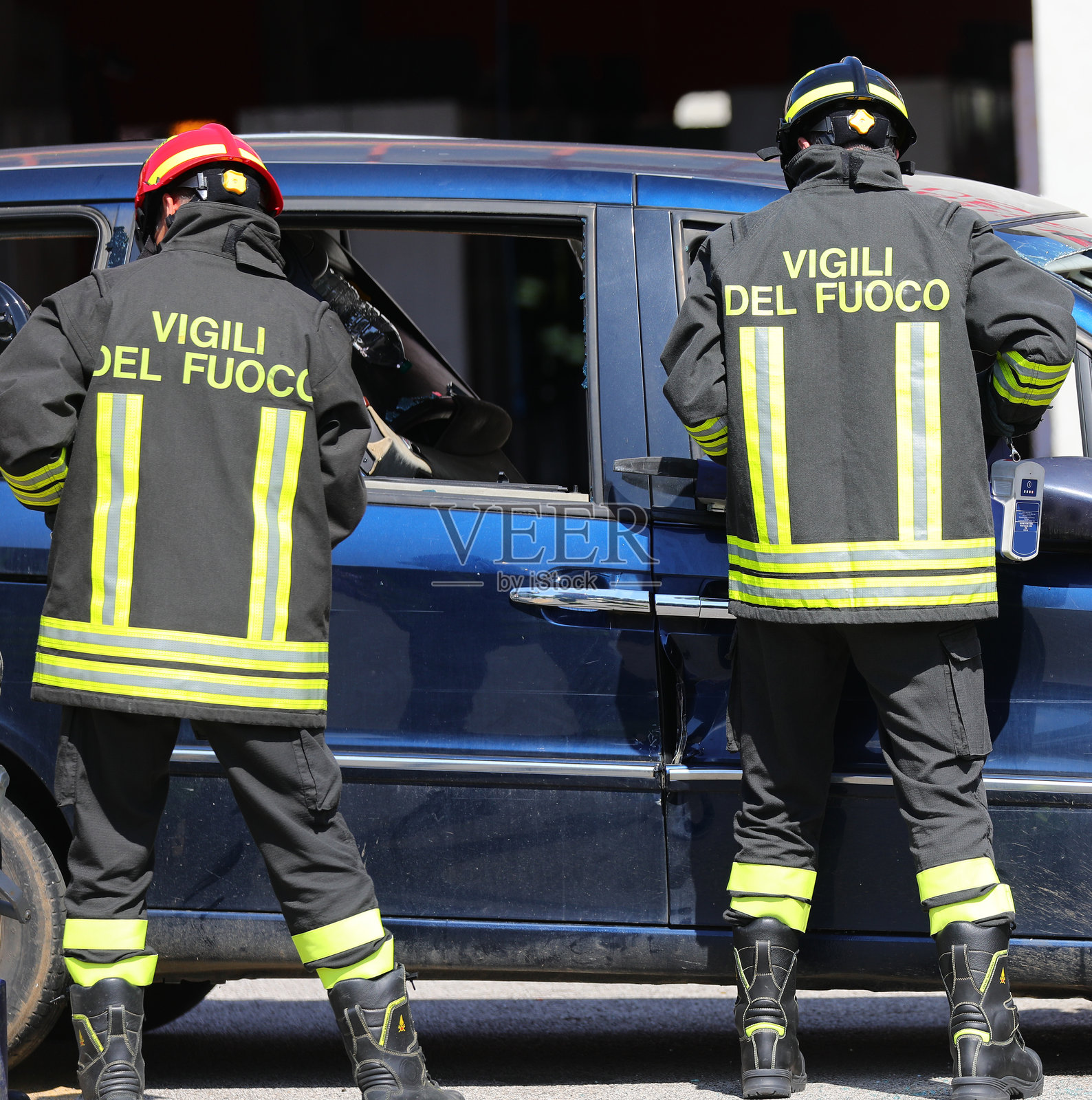 穿着制服的消防员在车祸现场帮助，背上写着大字。照片摄影图片