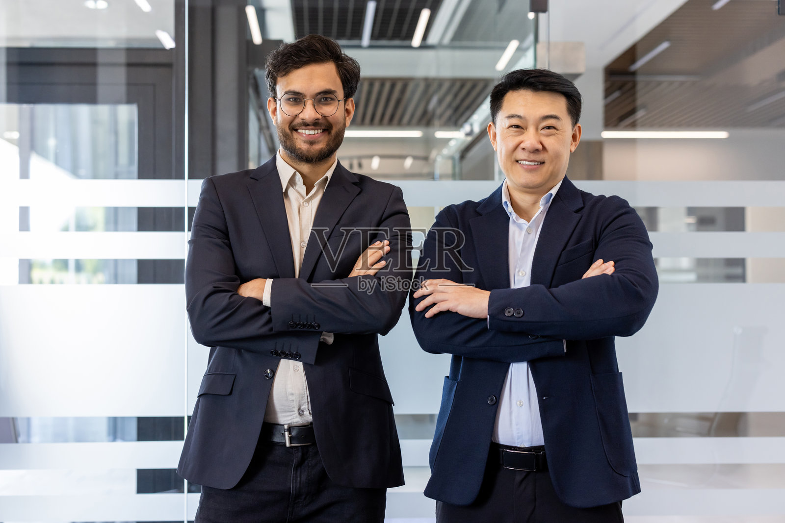 自信的商人在现代办公室中双臂交叉，展现领导力和团队合作精神照片摄影图片