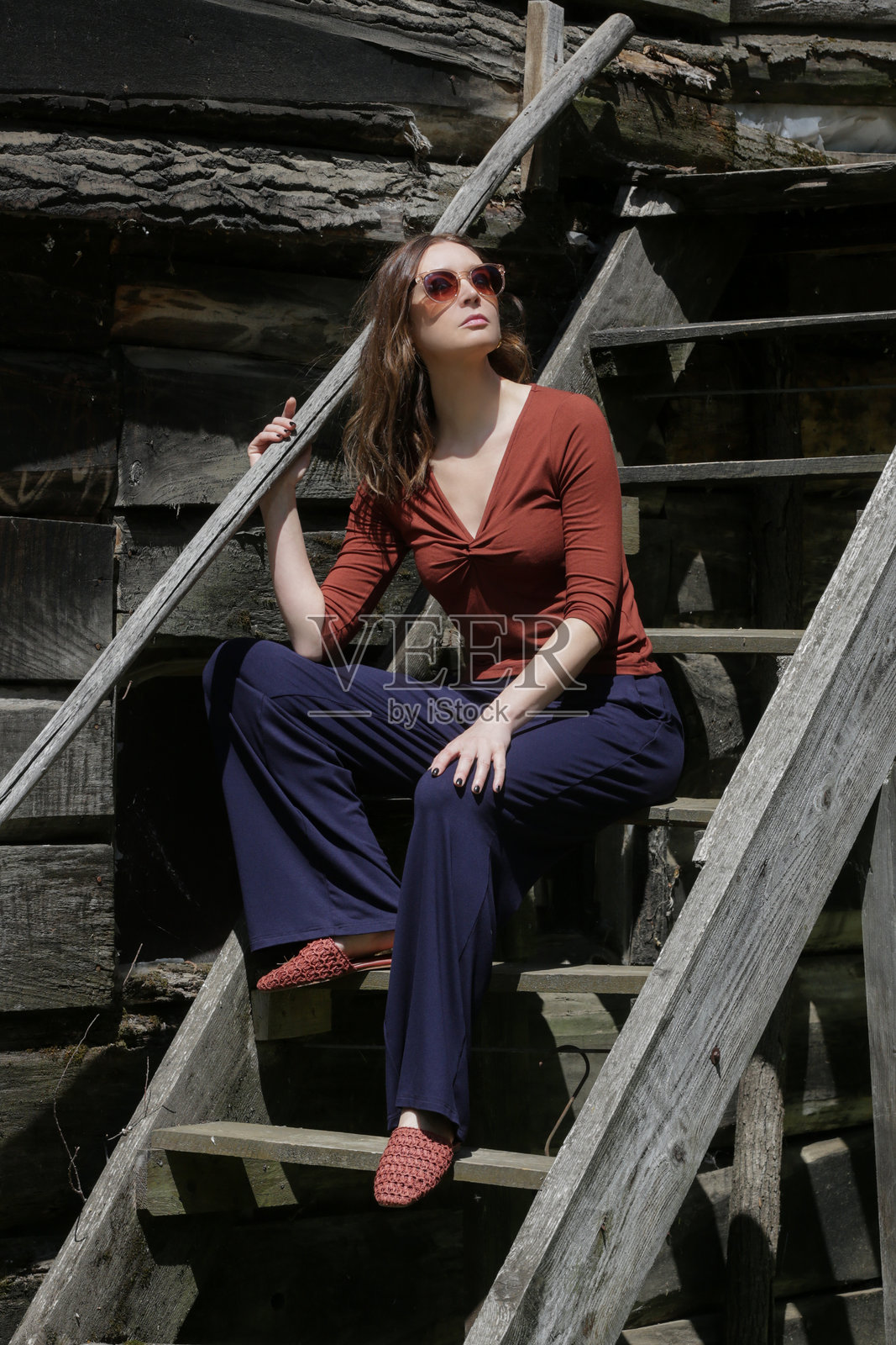 穿着休闲服装的女性，棕色棉质衬衫和蓝色裤子，在乡村享受宁静的夏日。照片摄影图片