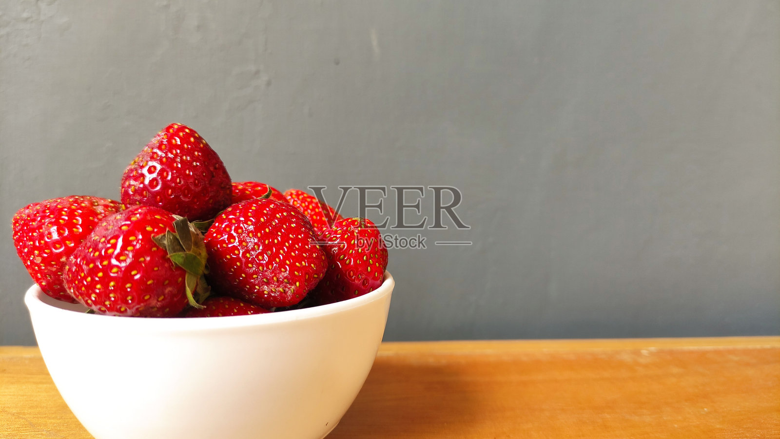 新鲜的红草莓放在木桌上照片摄影图片