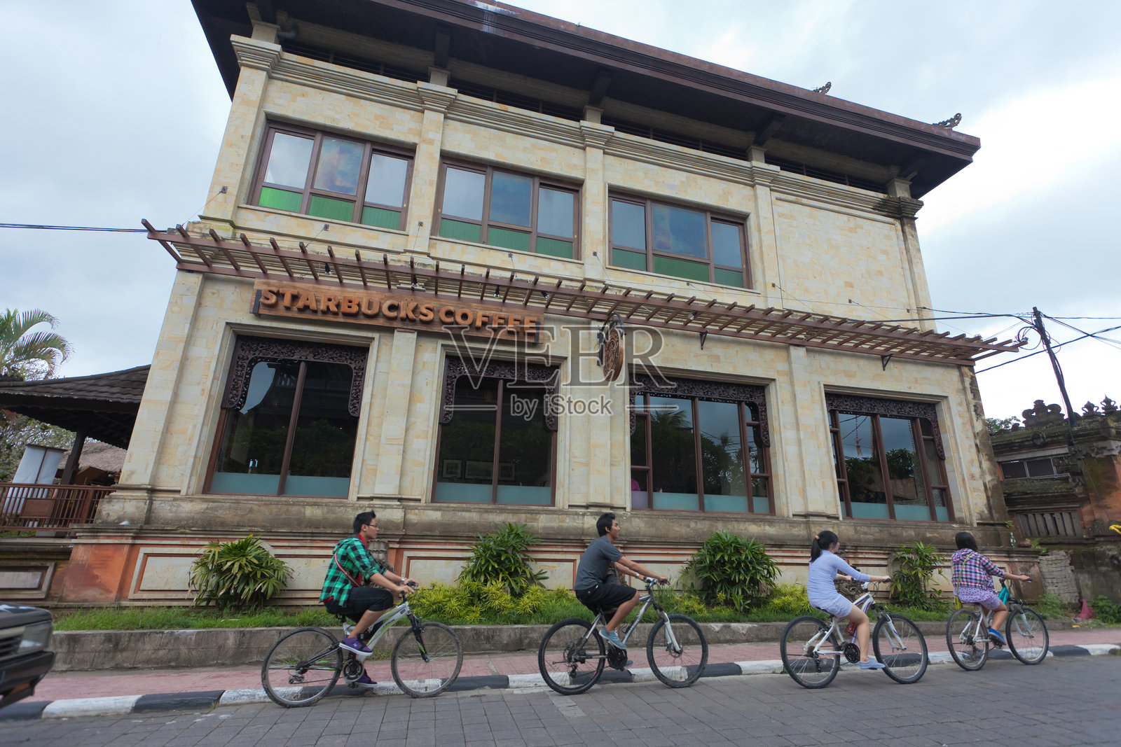 人们在星巴克旁骑自行车照片摄影图片