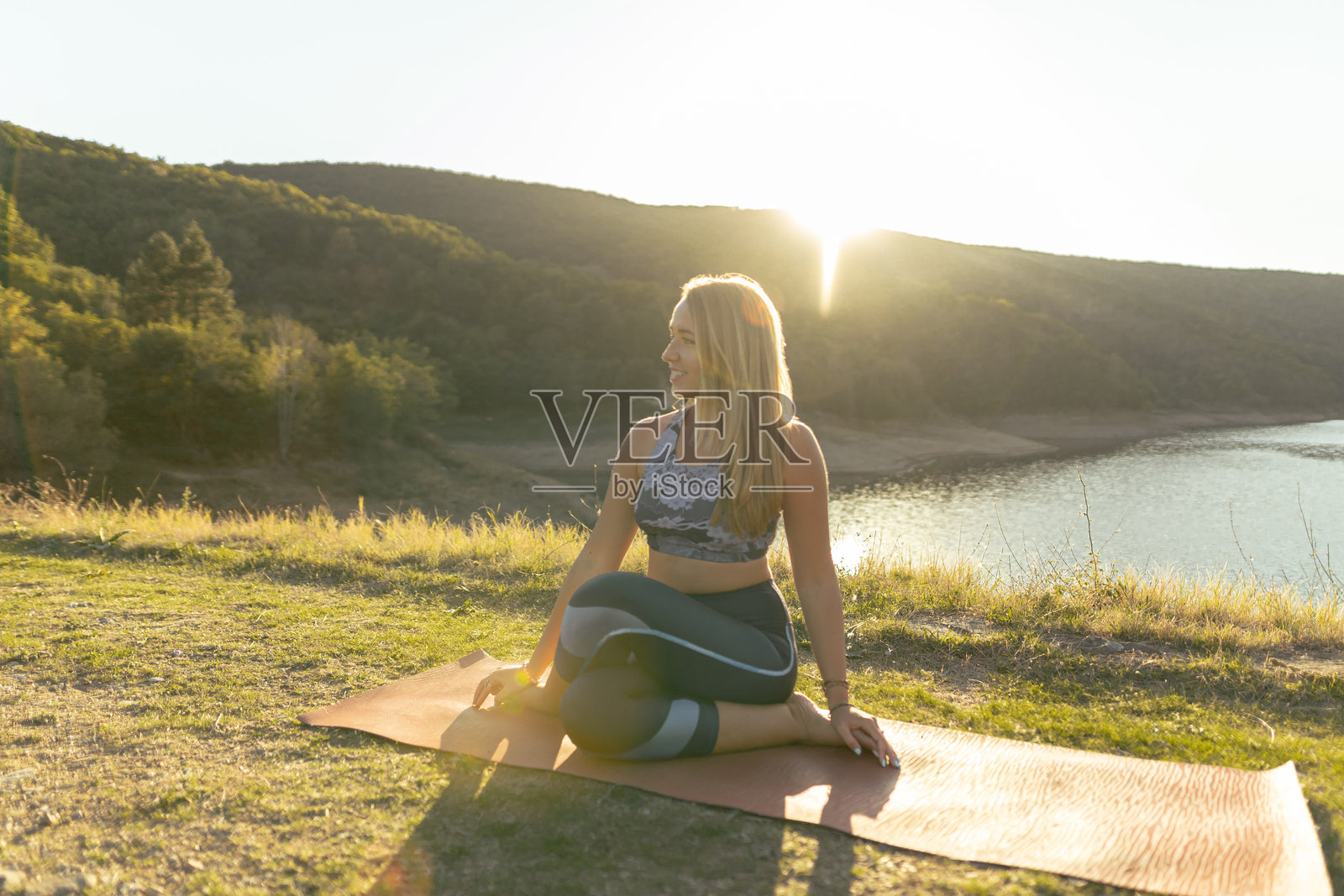 年轻迷人的微笑女性在湖边练习瑜伽照片摄影图片
