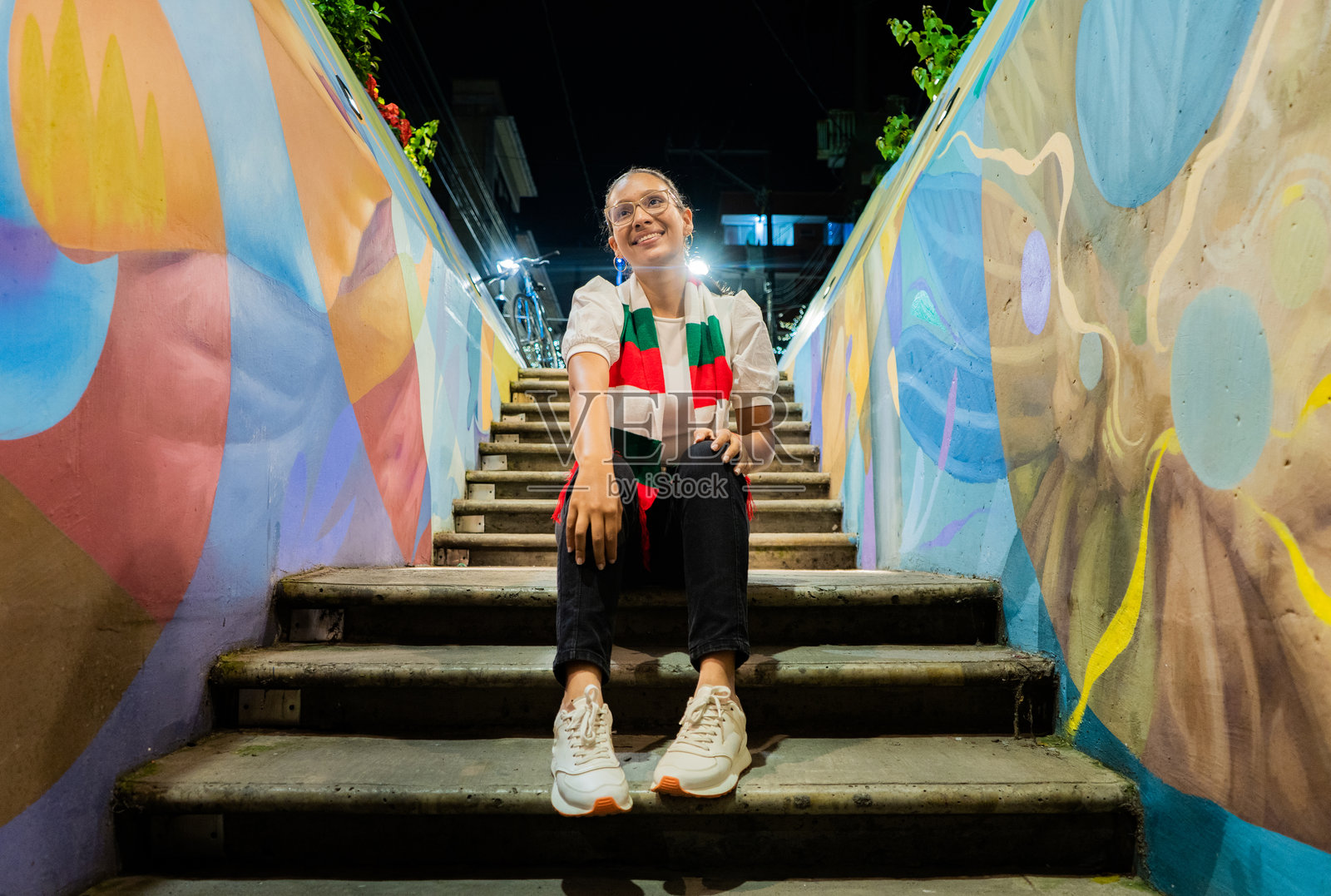 一位年轻女性坐在户外的台阶上。照片摄影图片