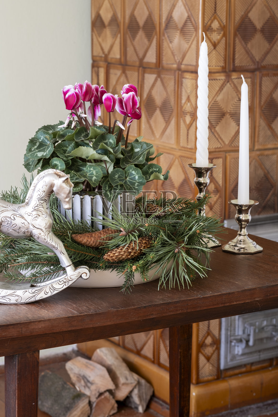 室内的圣诞装饰是一盆带有松果的波纹陶瓷花盆中的仙客来花，周围装饰着松枝花环。圣诞静物。照片摄影图片