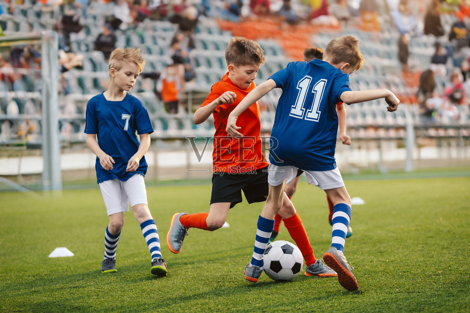 一群男孩足球队在比赛中争夺球权。孩子们在体育场上进行体育活动。快乐的孩子们在草坪上踢足球。穿着红色和蓝色足球队服的孩子们在比赛中。照片摄影图片