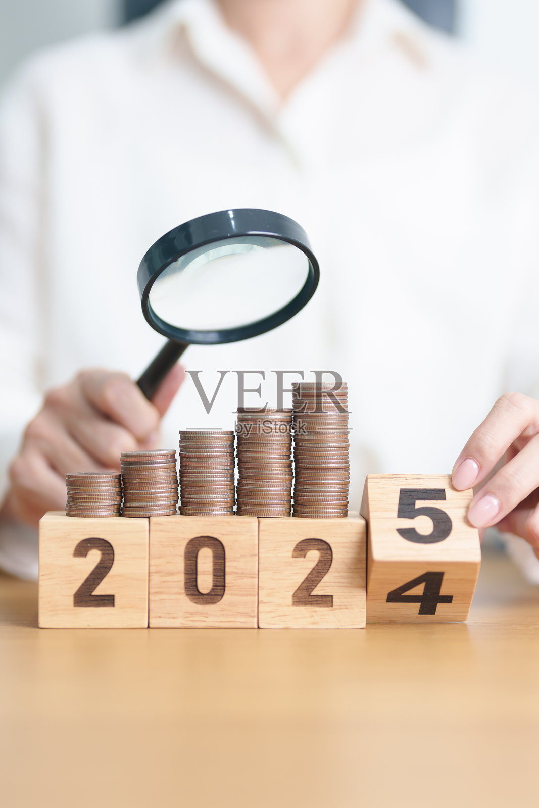 2024年结束到2025年新年快乐，随着放大镜的帮助，钱币堆积不断增长。储蓄、通货膨胀、税收、现金流、求职、招聘和研发概念。照片摄影图片