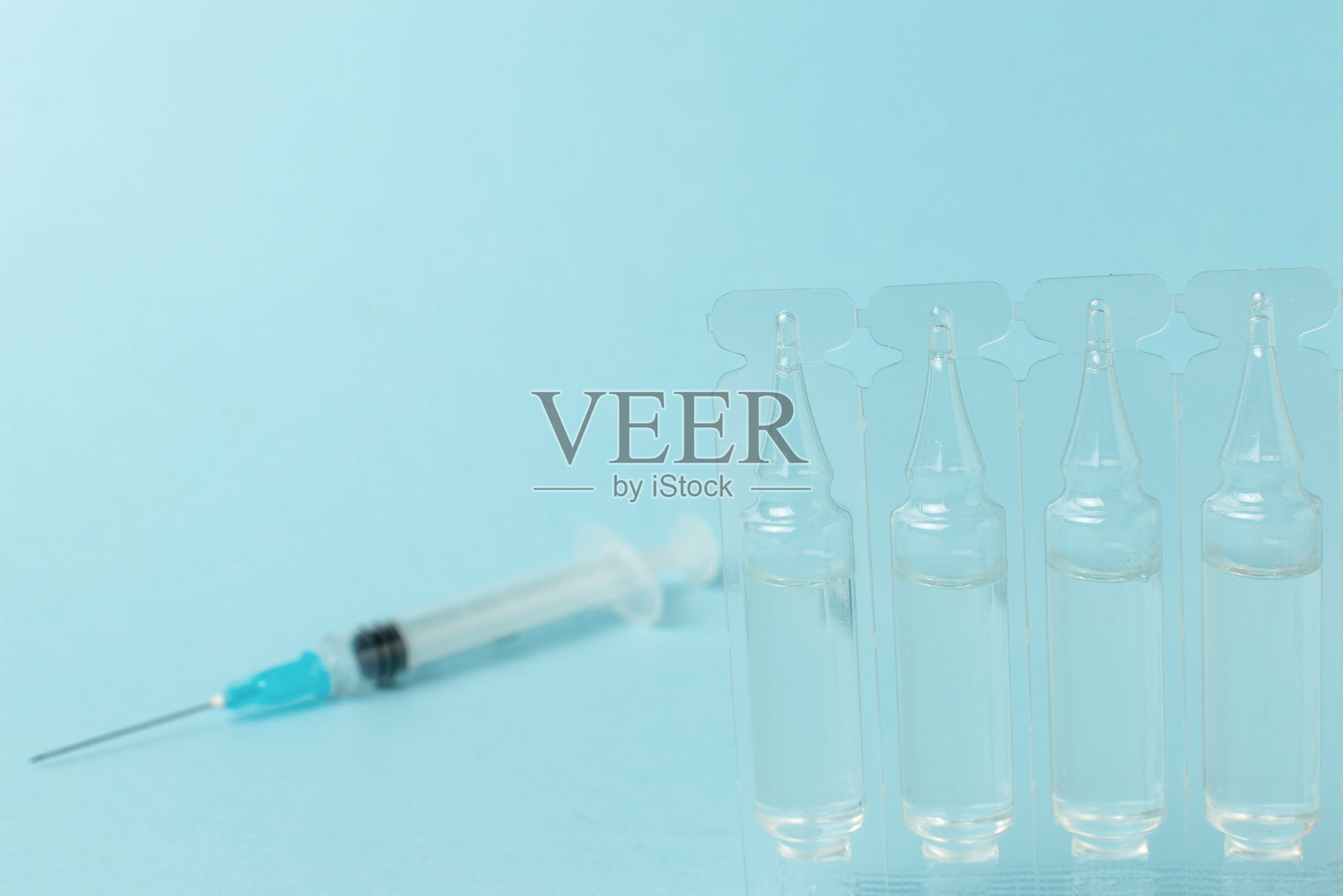 蓝色背景上的医疗安瓿和注射器：医疗保健与疫苗接种概念照片摄影图片