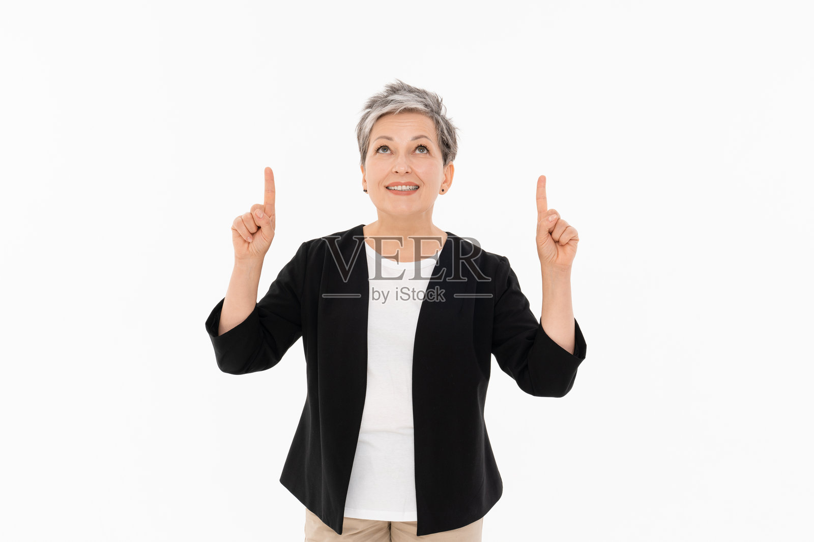 微笑的成熟的女商人指向空白的上方，背景为白色。照片摄影图片
