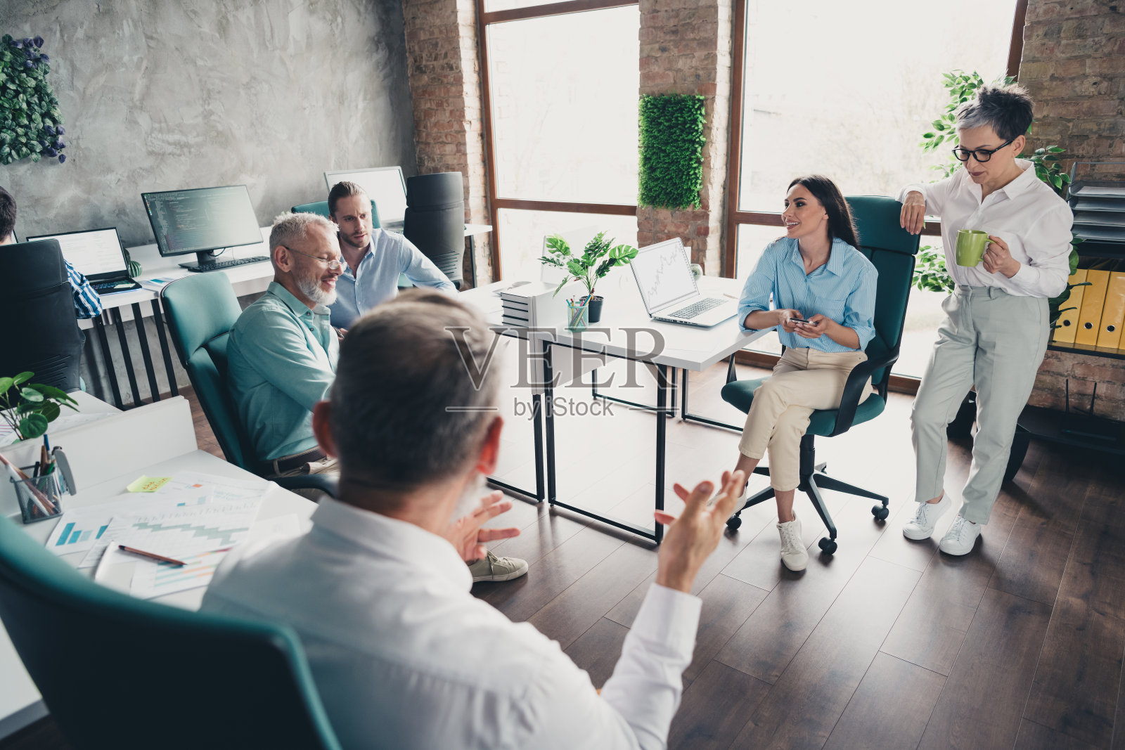 全景照片，展示了在明亮的办公室中，团队成员围成一圈讨论工作，进行成功的会议。照片摄影图片