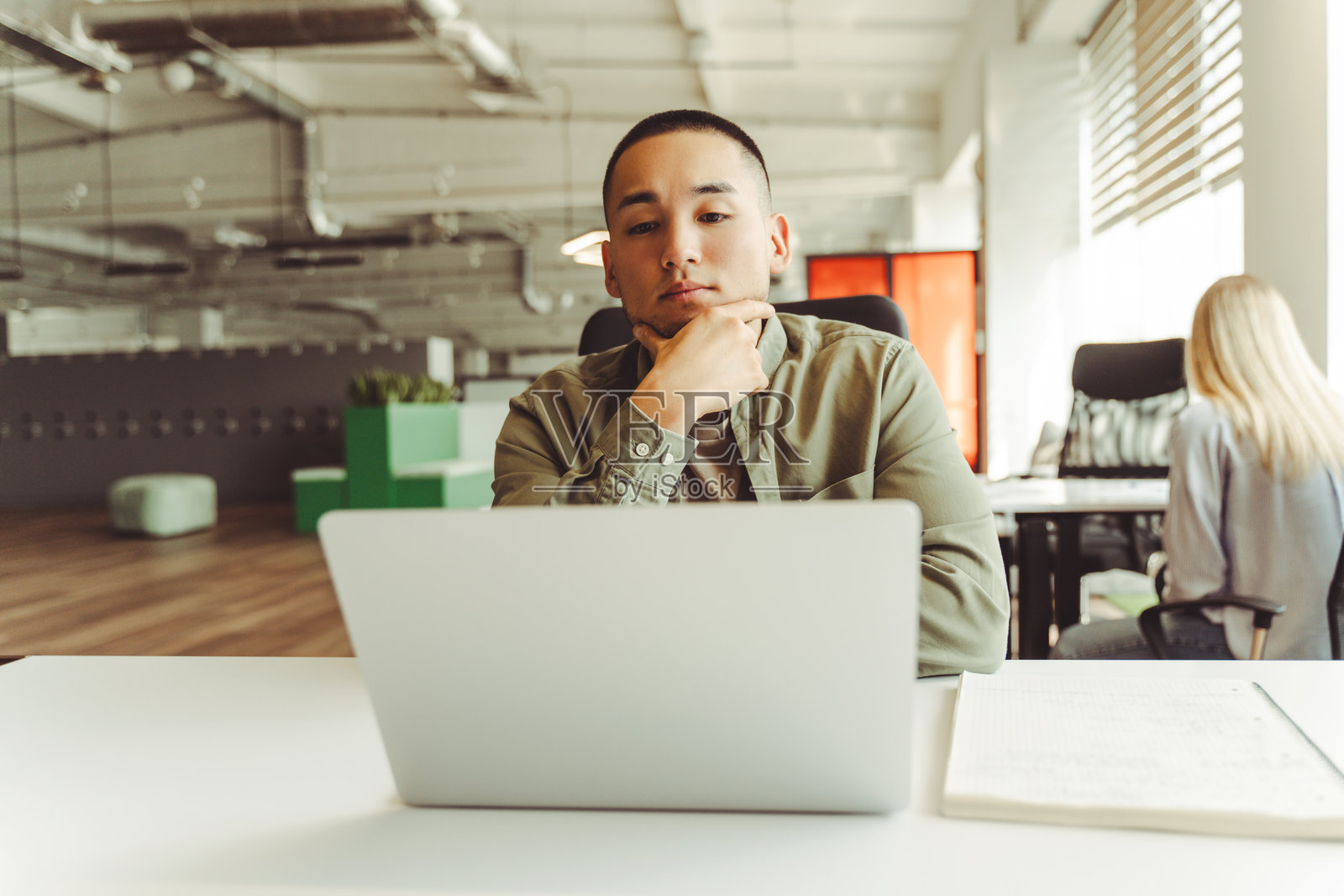 专注的亚洲商人在现代办公室使用笔记本电脑工作照片摄影图片