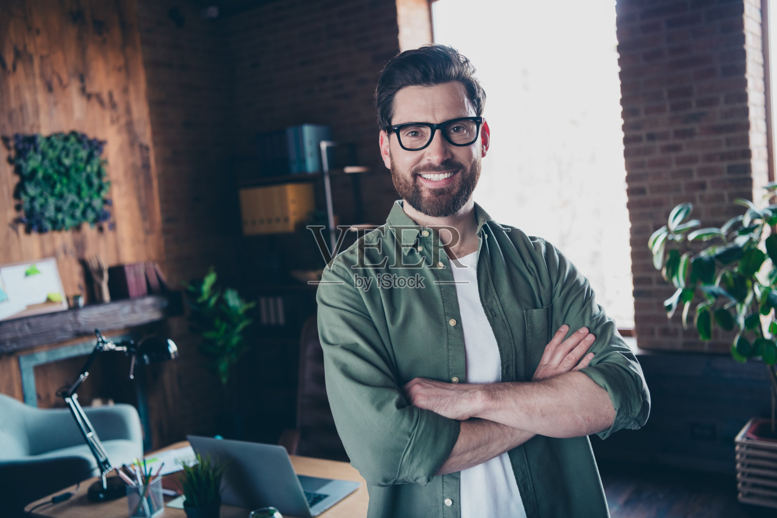 穿着衬衫、微笑并双臂交叉的聪明领导者在室内工作站工作坊的照片照片摄影图片