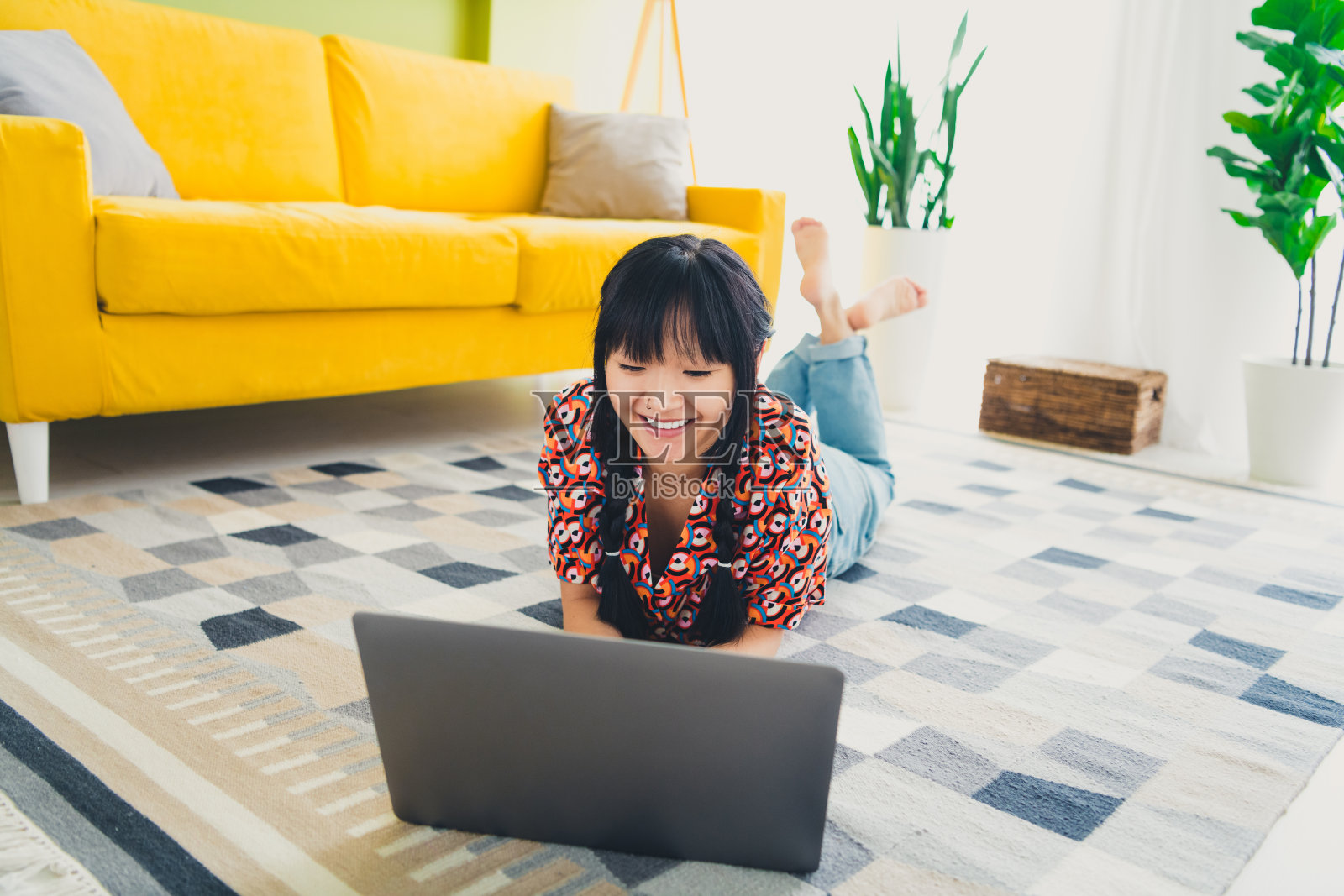 年轻漂亮的女子在现代公寓的地板上使用笔记本电脑，享受周末时光。照片摄影图片