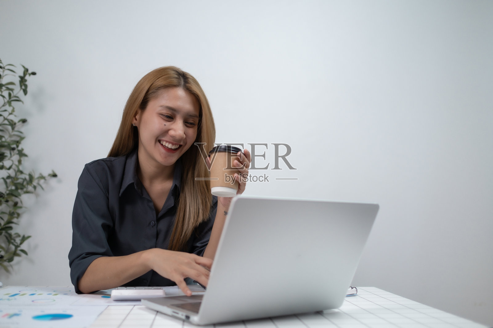 专注的职业女性在家中的客厅使用笔记本电脑，职业女性在办公室使用笔记本电脑阅读财务报告。照片摄影图片