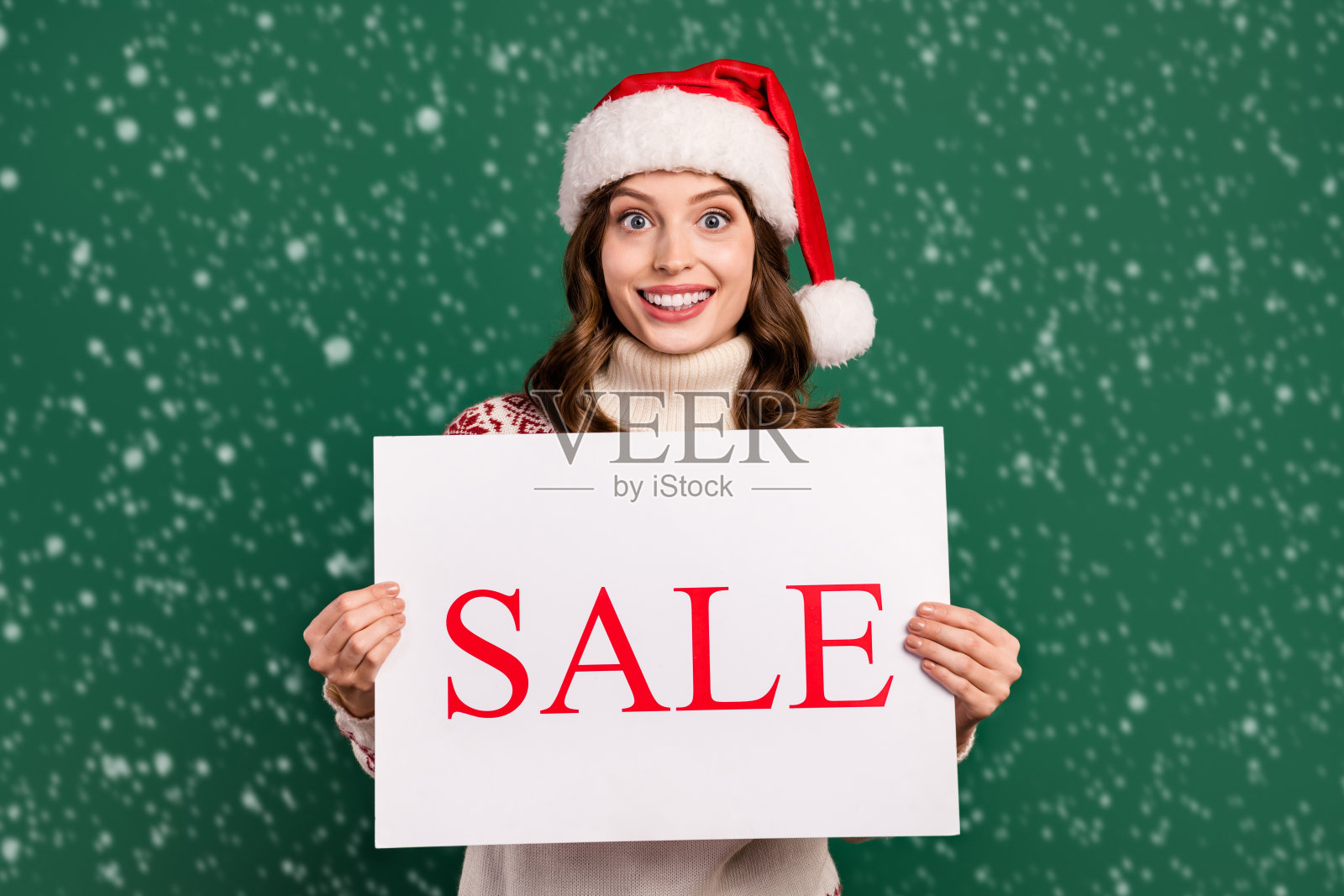 积极美丽的女士手持空白纸质促销广告，背景为绿色。照片摄影图片