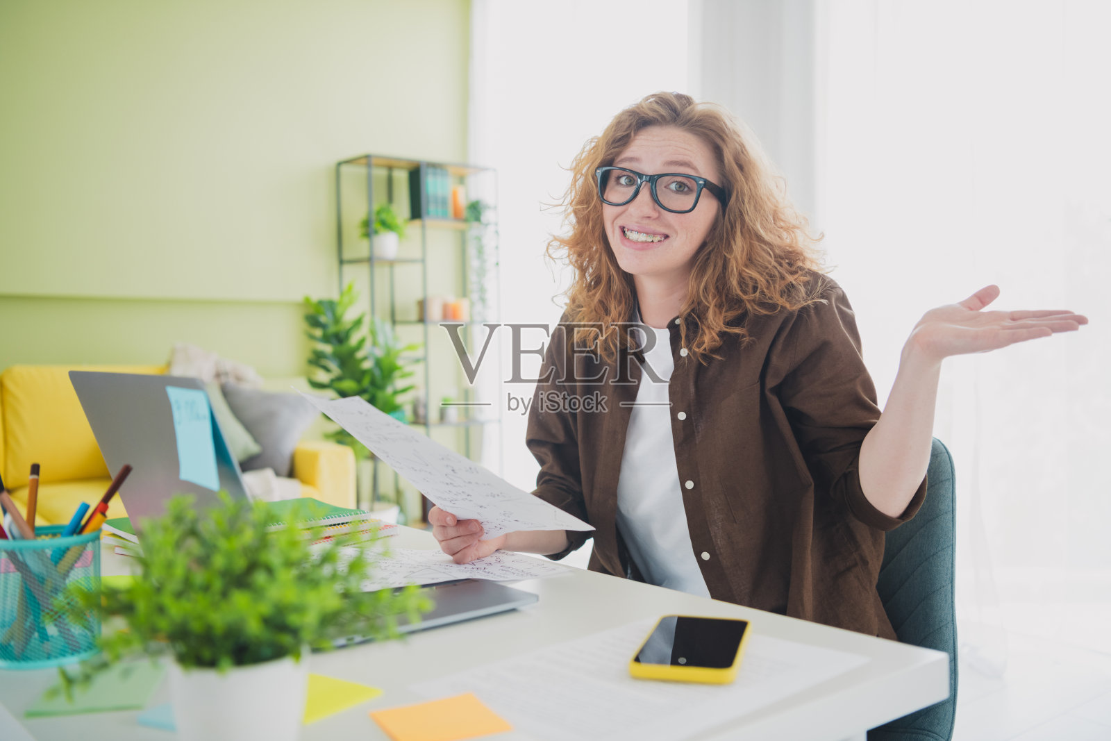 可爱迷人的女孩穿着衬衫坐在桌子前在家做作业，学习于室内工作空间。照片摄影图片
