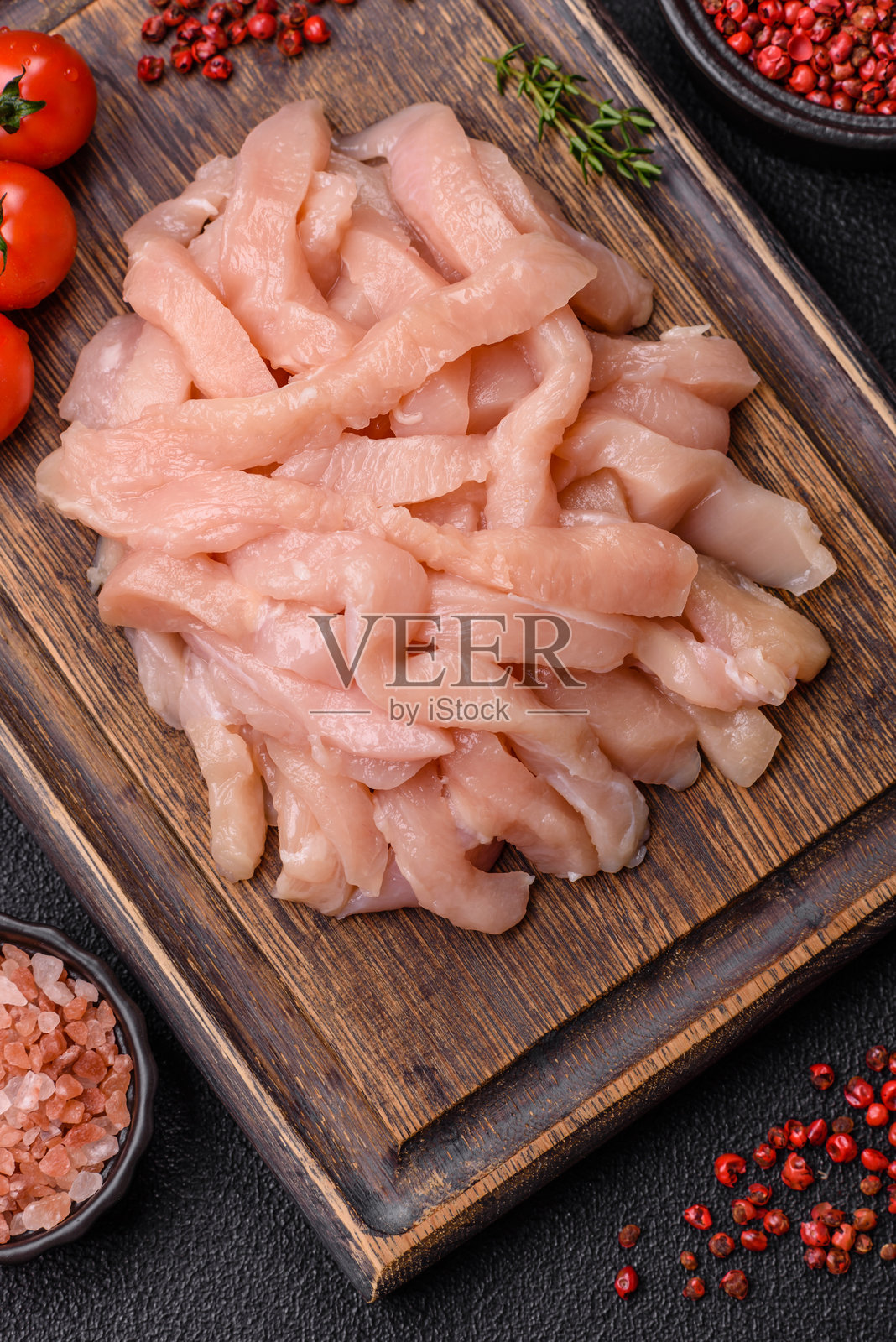 切成条状的生鸡胸肉，撒上香料和草药照片摄影图片