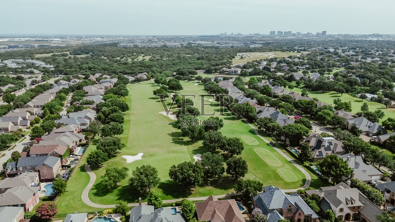 高档住宅区内的乡村俱乐部全景鸟瞰图，背景是德克萨斯州普莱诺市中心，绿草如茵的高尔夫球场、沙坑、两层住宅和游泳池。照片摄影图片