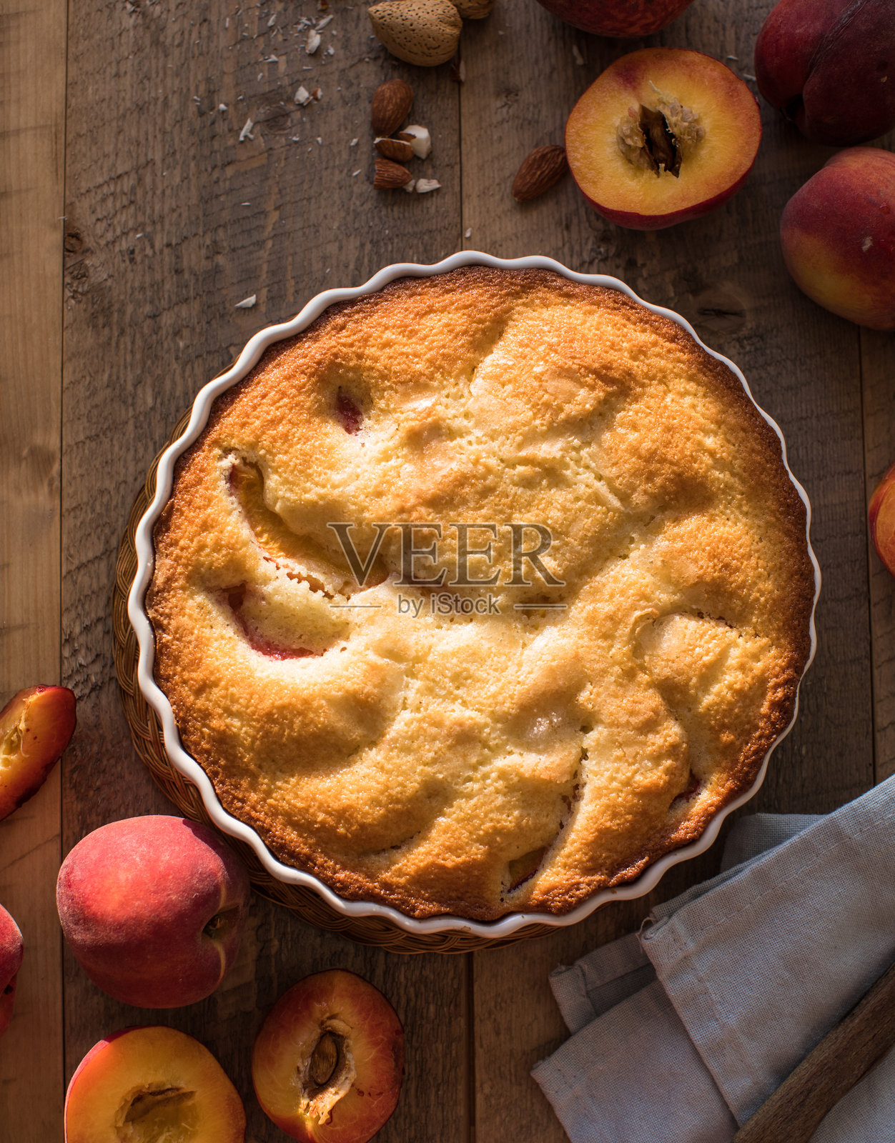 厨房木桌上的自制桃子派，背景是一本食谱，撒上了糖粉和桃子。照片摄影图片