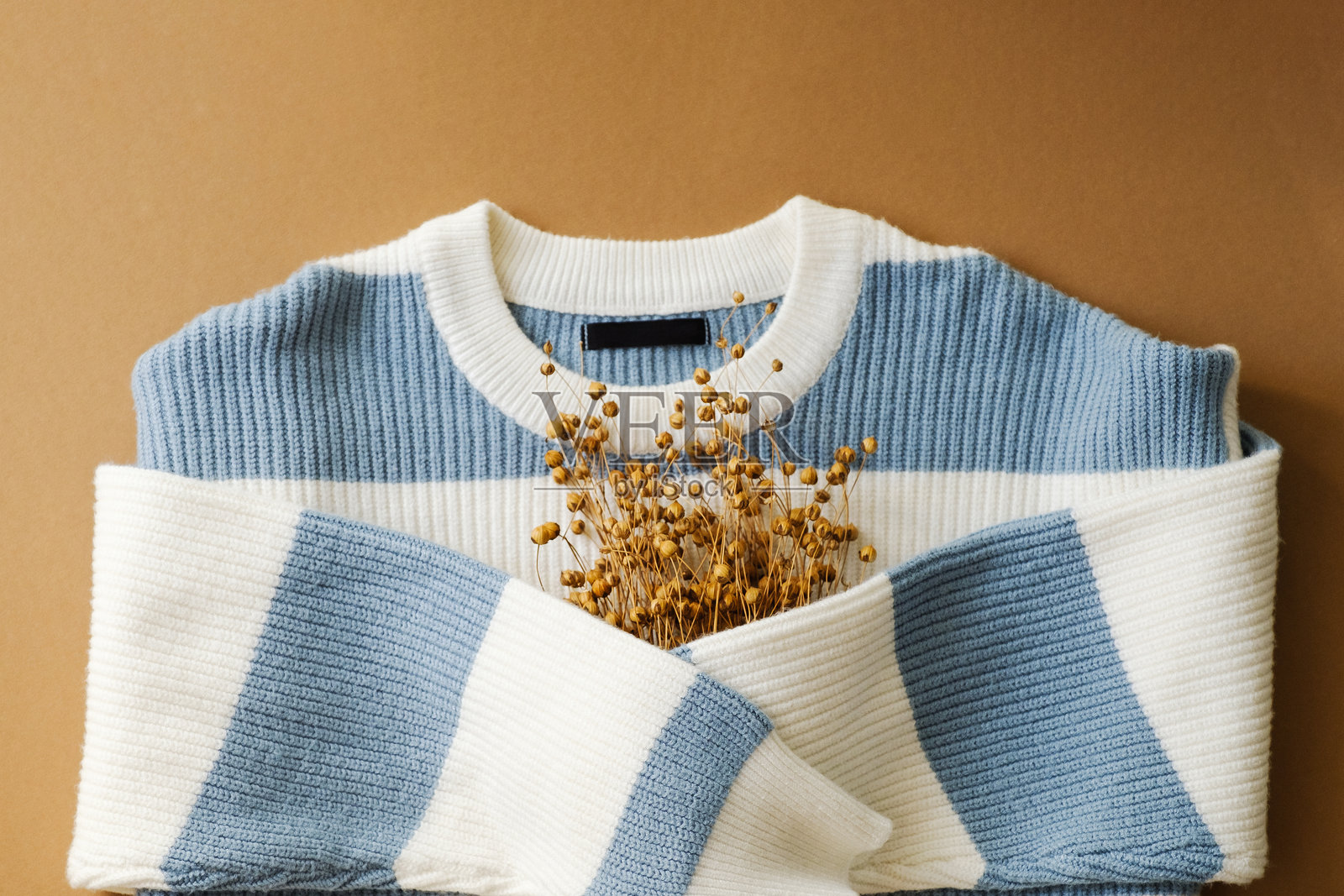 舒适的浅蓝色和白色条纹毛衣，搭配乡村风格的干花。非常适合时尚、生活方式和家居装饰主题。照片摄影图片
