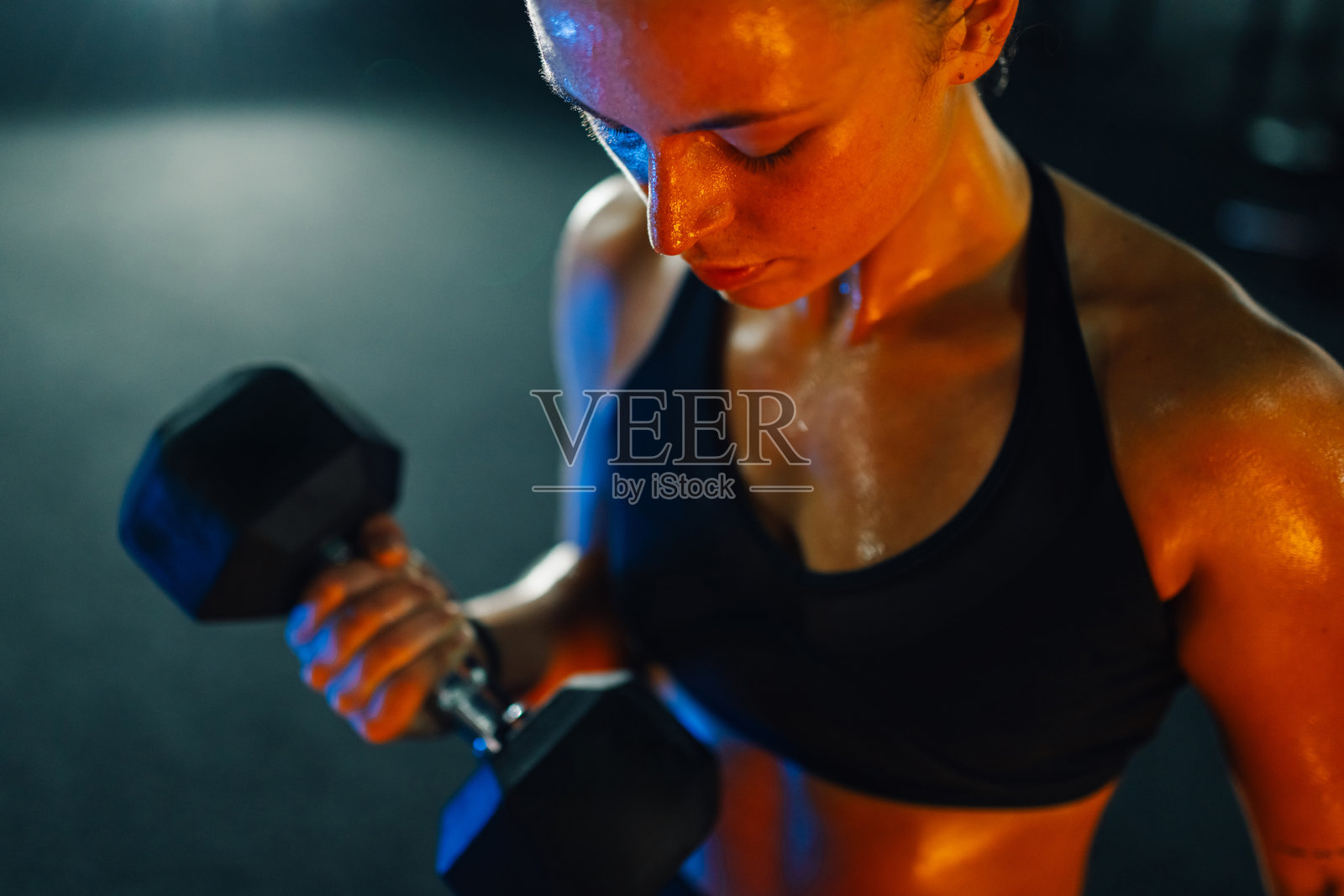 女运动员在健身房举哑铃训练二头肌照片摄影图片