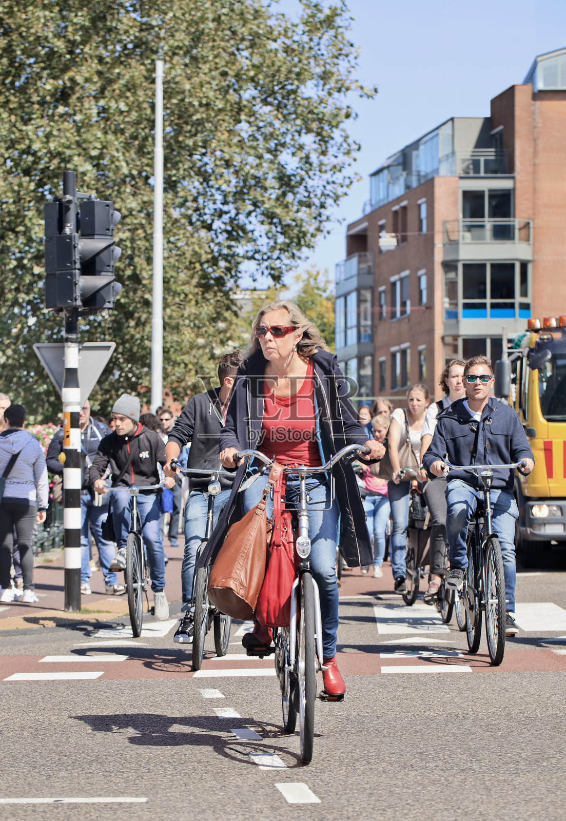 穿着休闲的成熟的女性在阳光明媚的阿姆斯特丹市中心骑自行车照片摄影图片