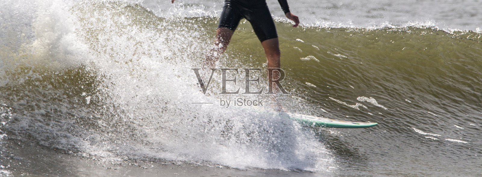 一名男子穿着黑色短潜水服在汹涌的海浪上冲浪照片摄影图片