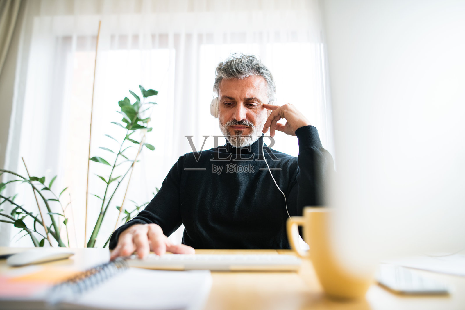 帅气男士的家庭办公室。男士在家中办公室工作时听音乐。远程办公。照片摄影图片