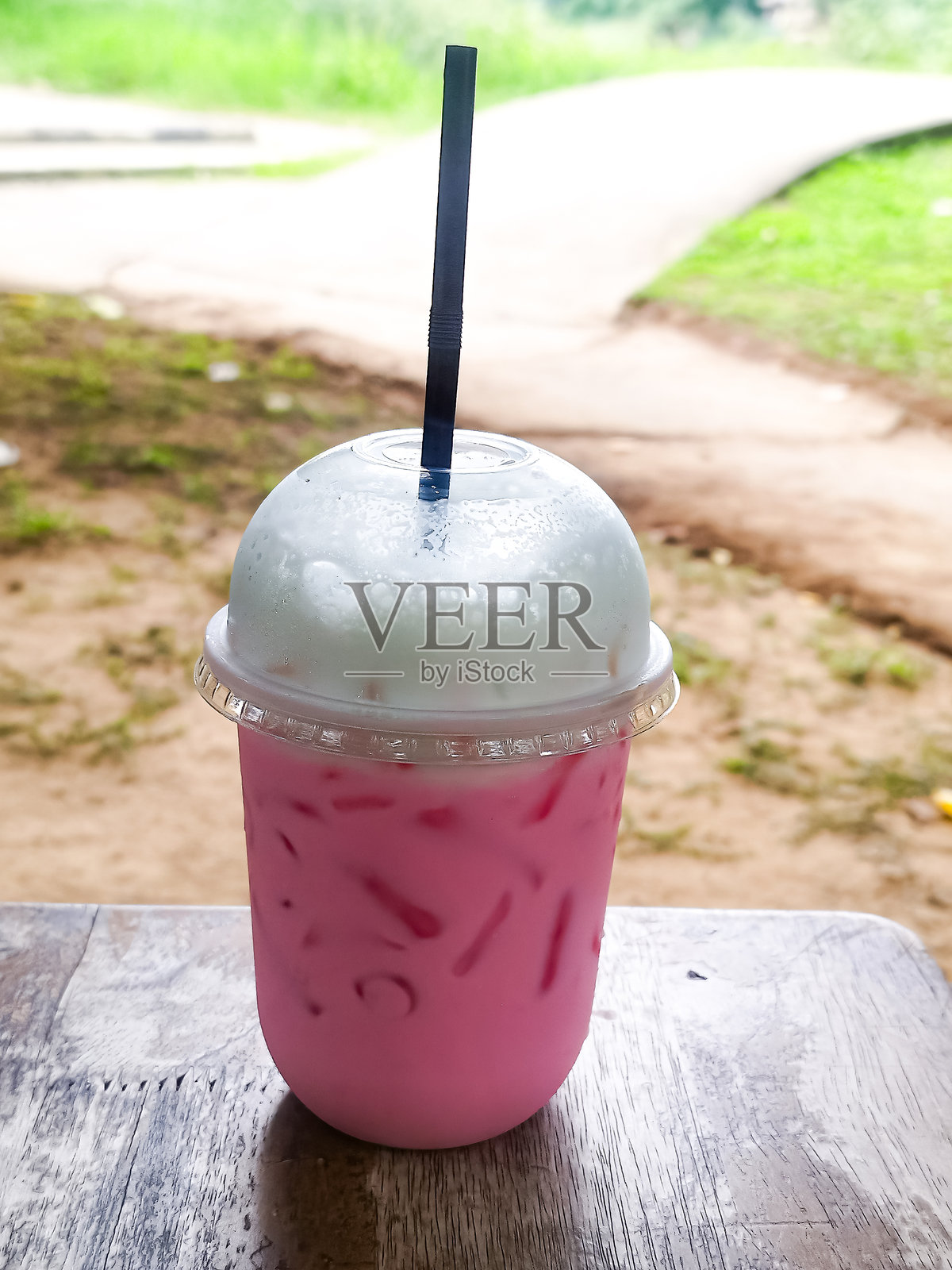 泰式粉红牛奶垂直照片，摆放在自然环境中的餐桌上，清迈，泰国。照片摄影图片