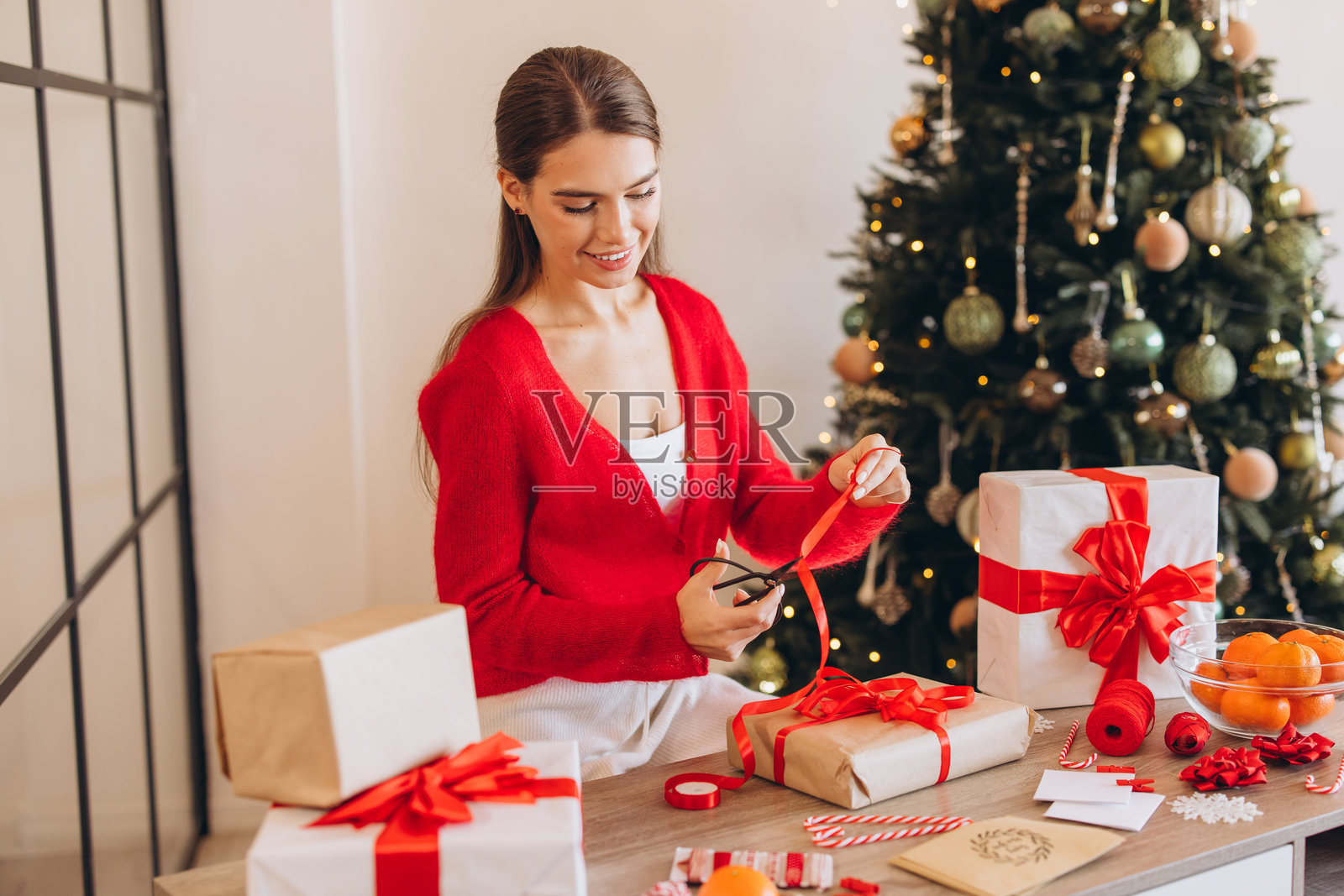 微笑的女性在装饰好的圣诞树旁包裹礼物照片摄影图片