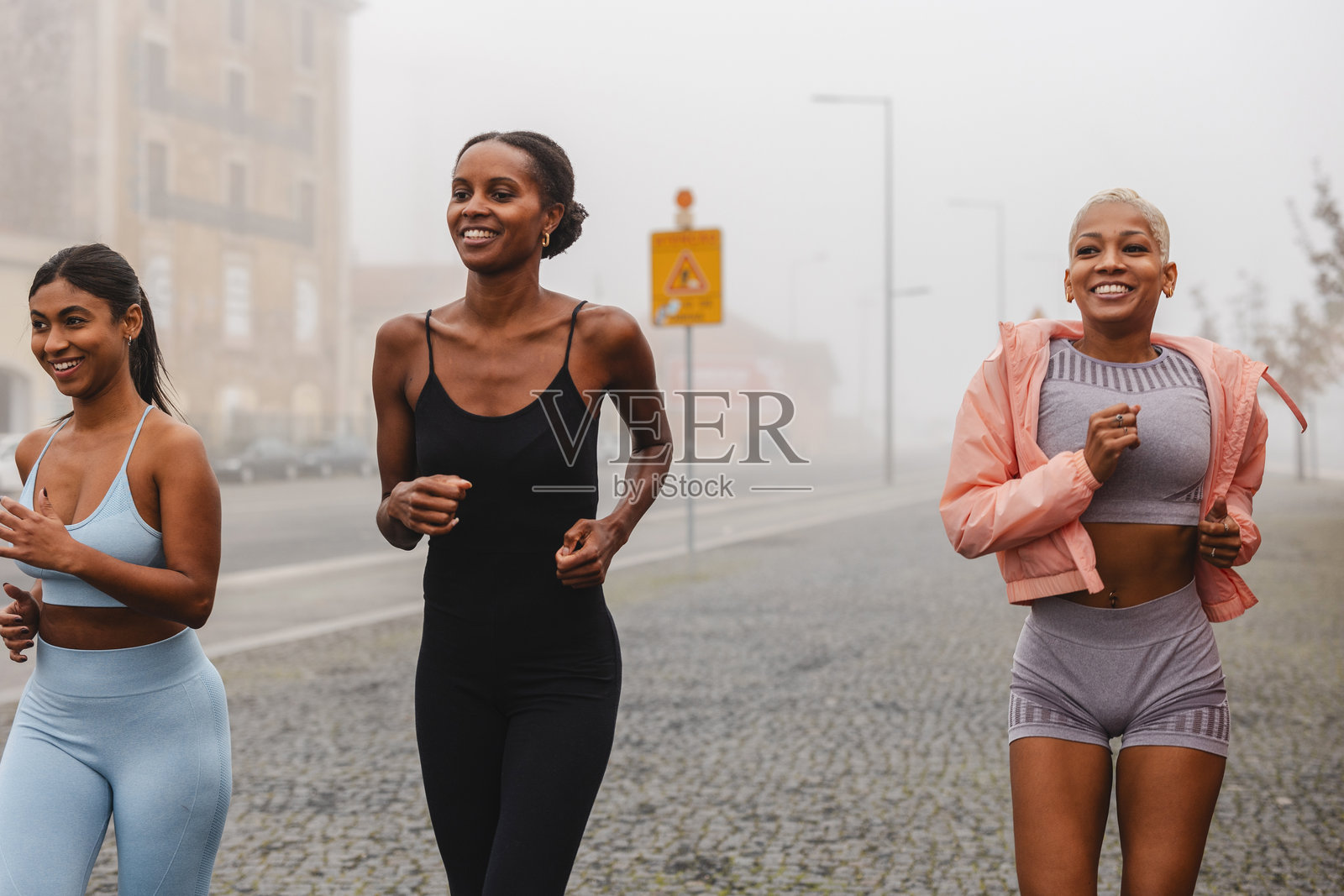 三名女性运动员在雾霭弥漫的城市中奔跑照片摄影图片