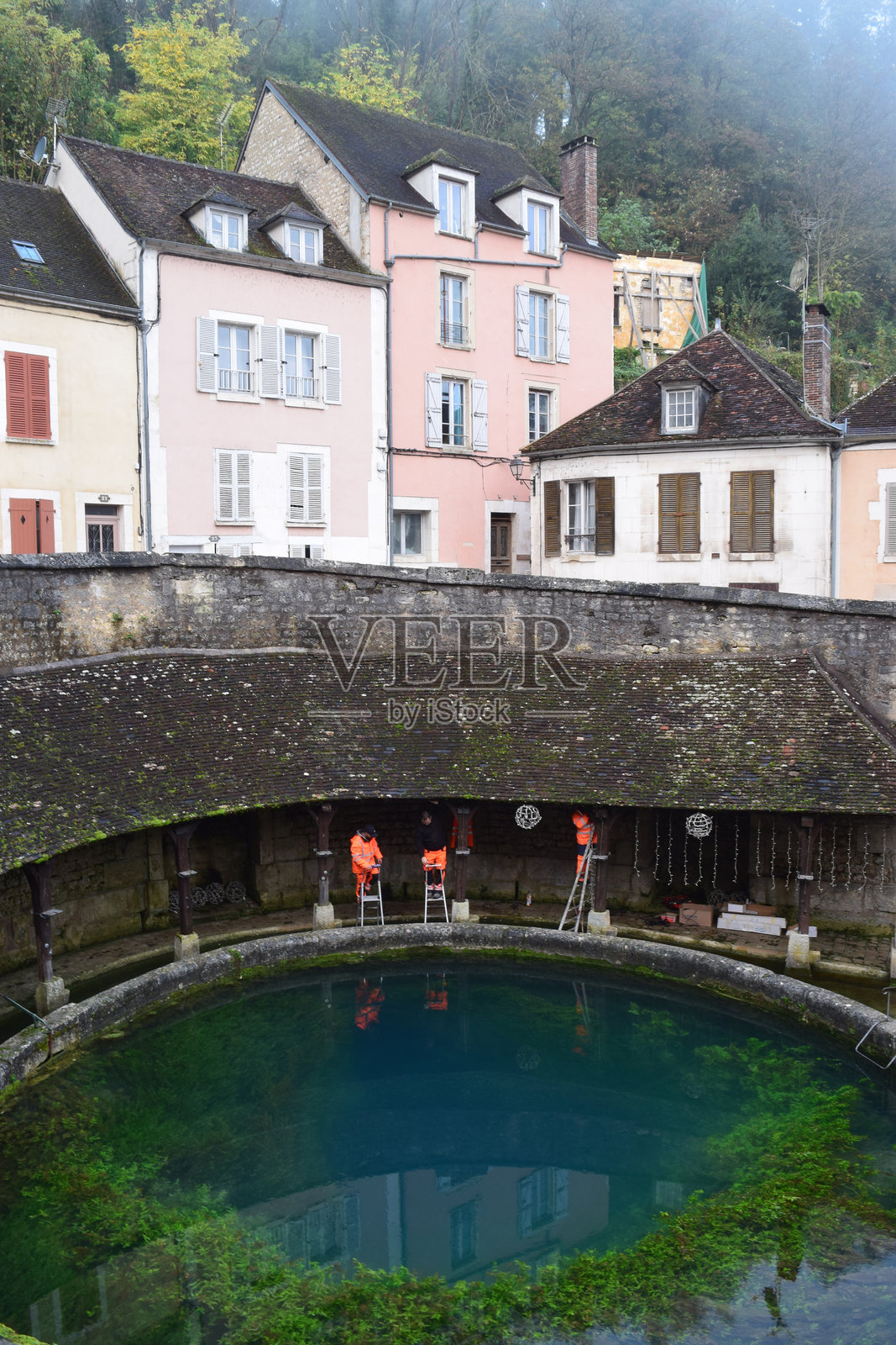 身穿橙色工作服的市政工作人员在托纳尔的福斯迪昂周围布置圣诞装饰。照片摄影图片