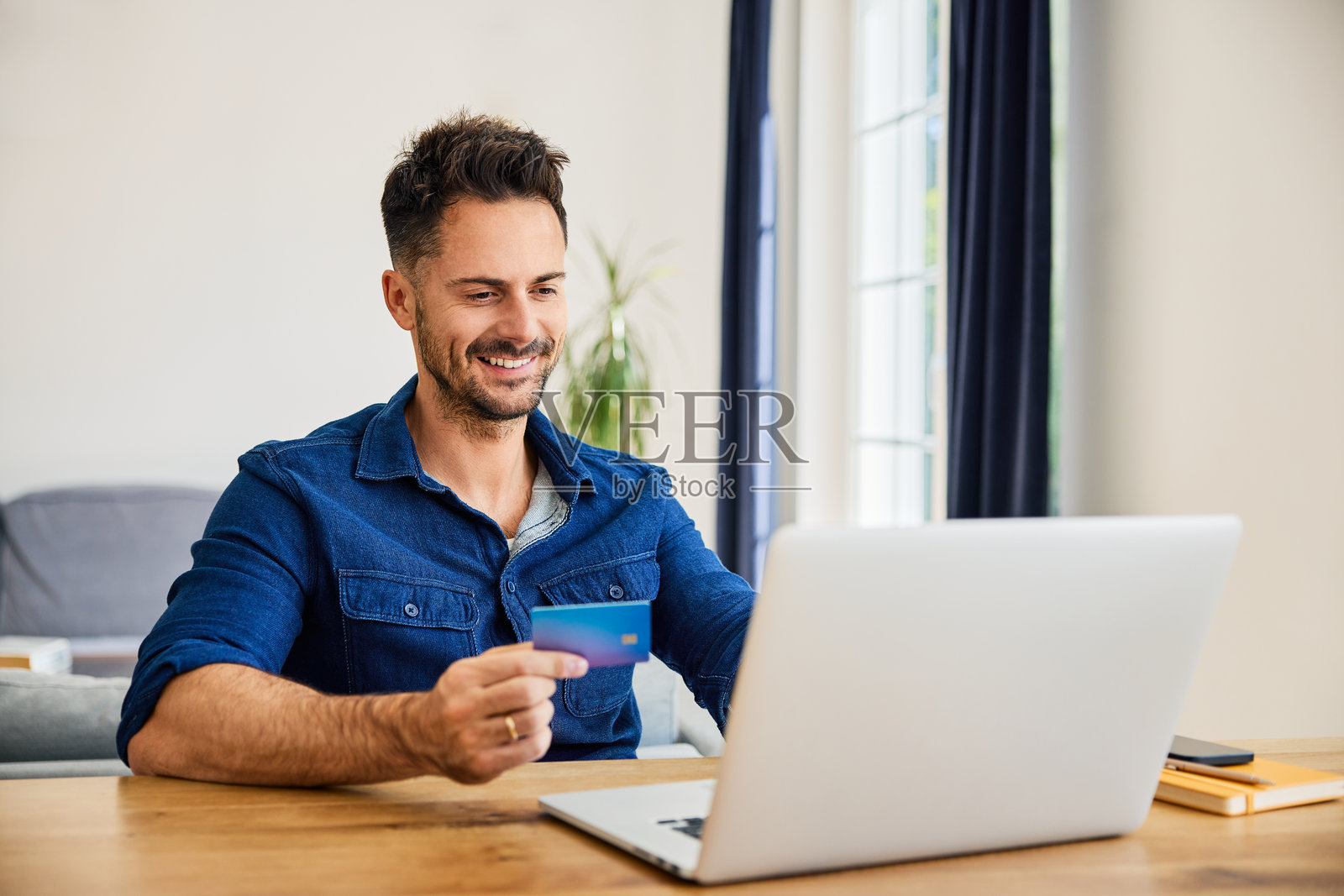 快乐的男人在家里使用笔记本电脑和信用卡进行在线购物照片摄影图片
