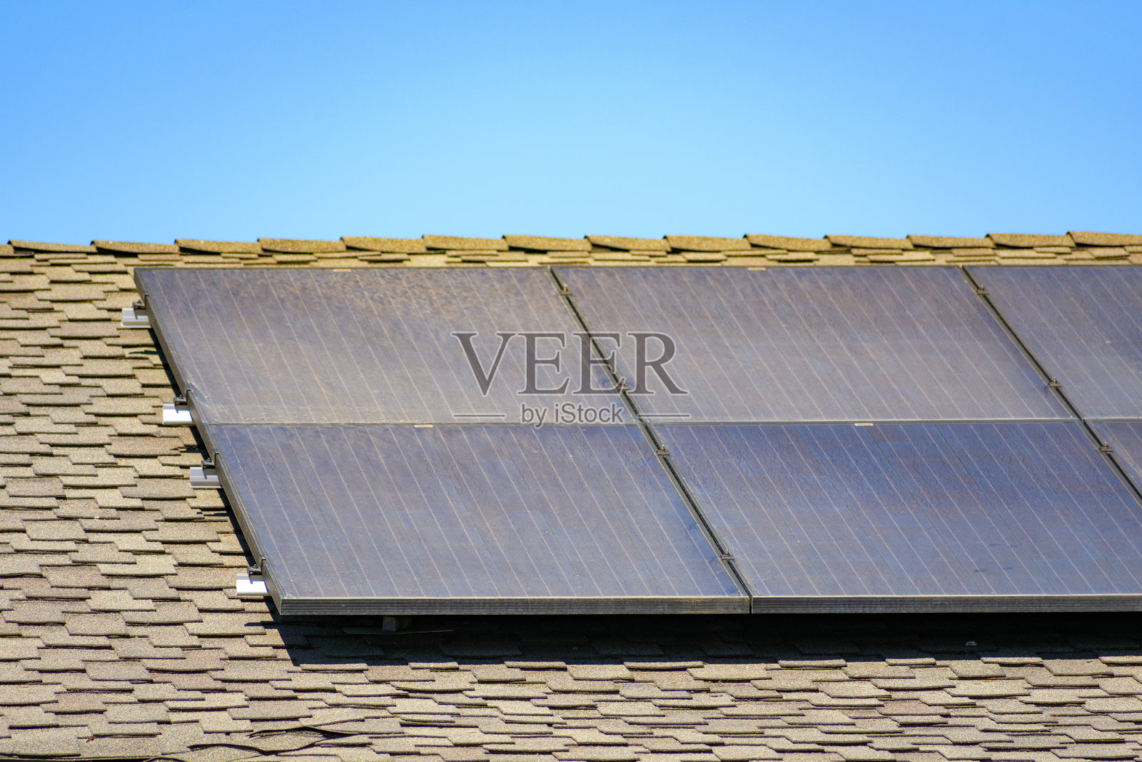 脏污的太阳能电池板安装在铺有沥青瓦的住宅屋顶上照片摄影图片