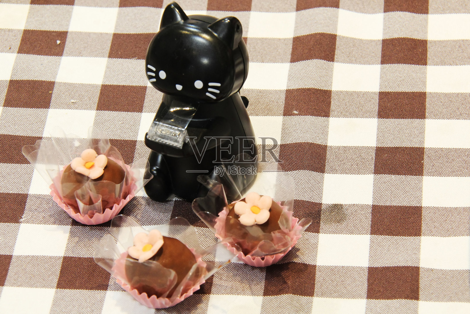 美味巧克力特写，上面装饰着椰子和粉色花朵，还有一只猫的装饰。照片摄影图片