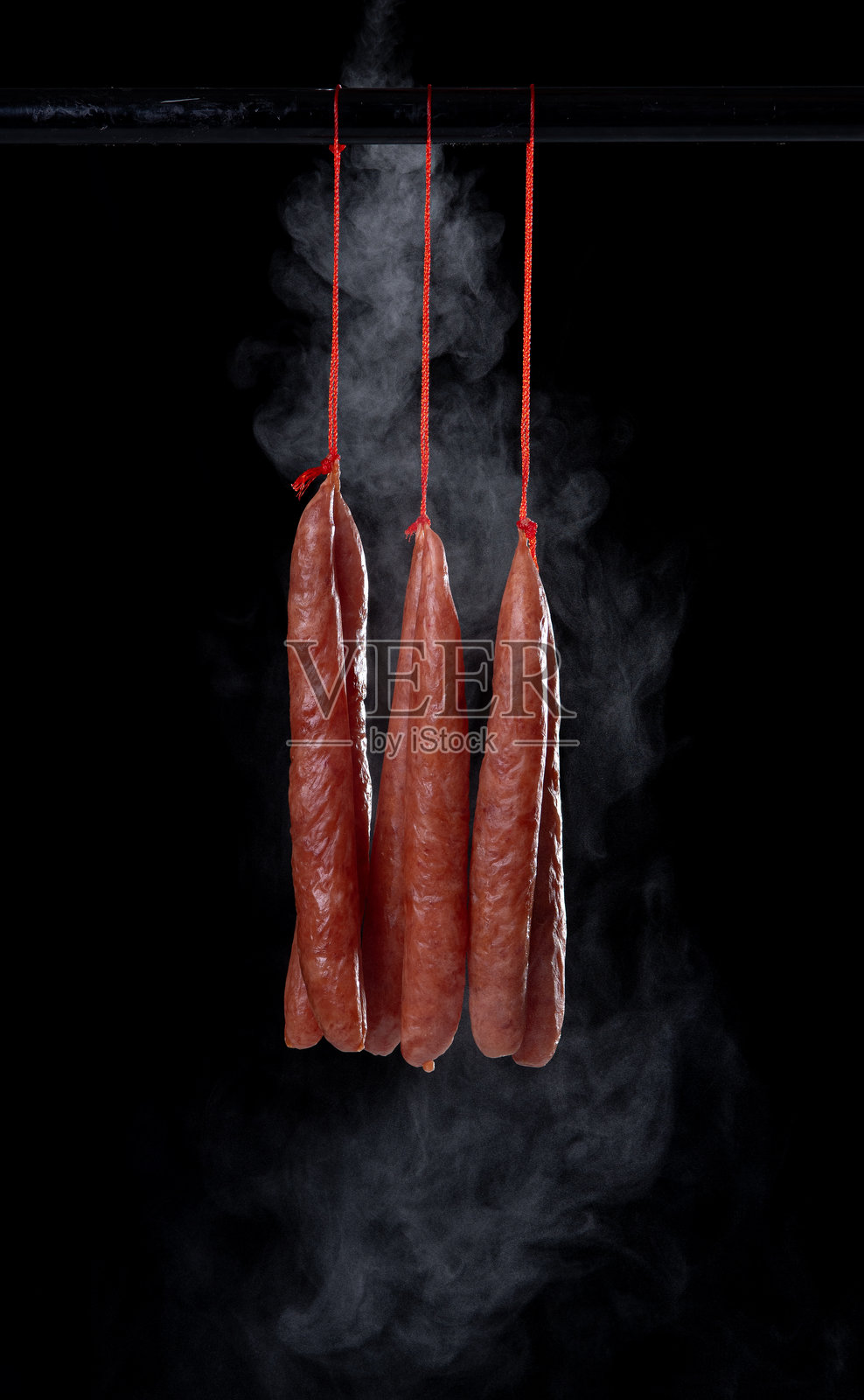 在深色背景上悬挂的干腊肠照片摄影图片