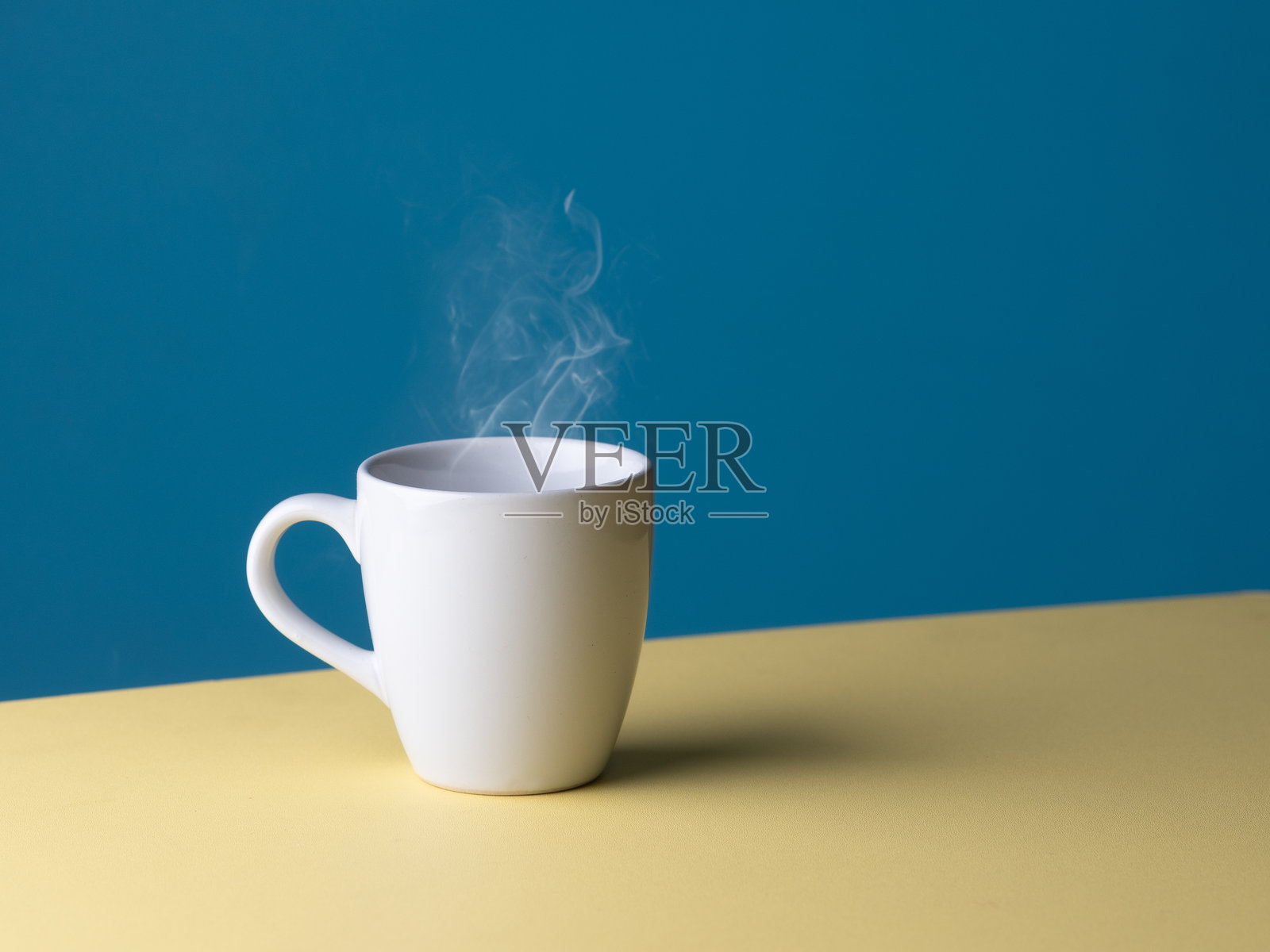 白色热咖啡杯，冒着烟雾，背景为淡蓝色，有留白空间照片摄影图片