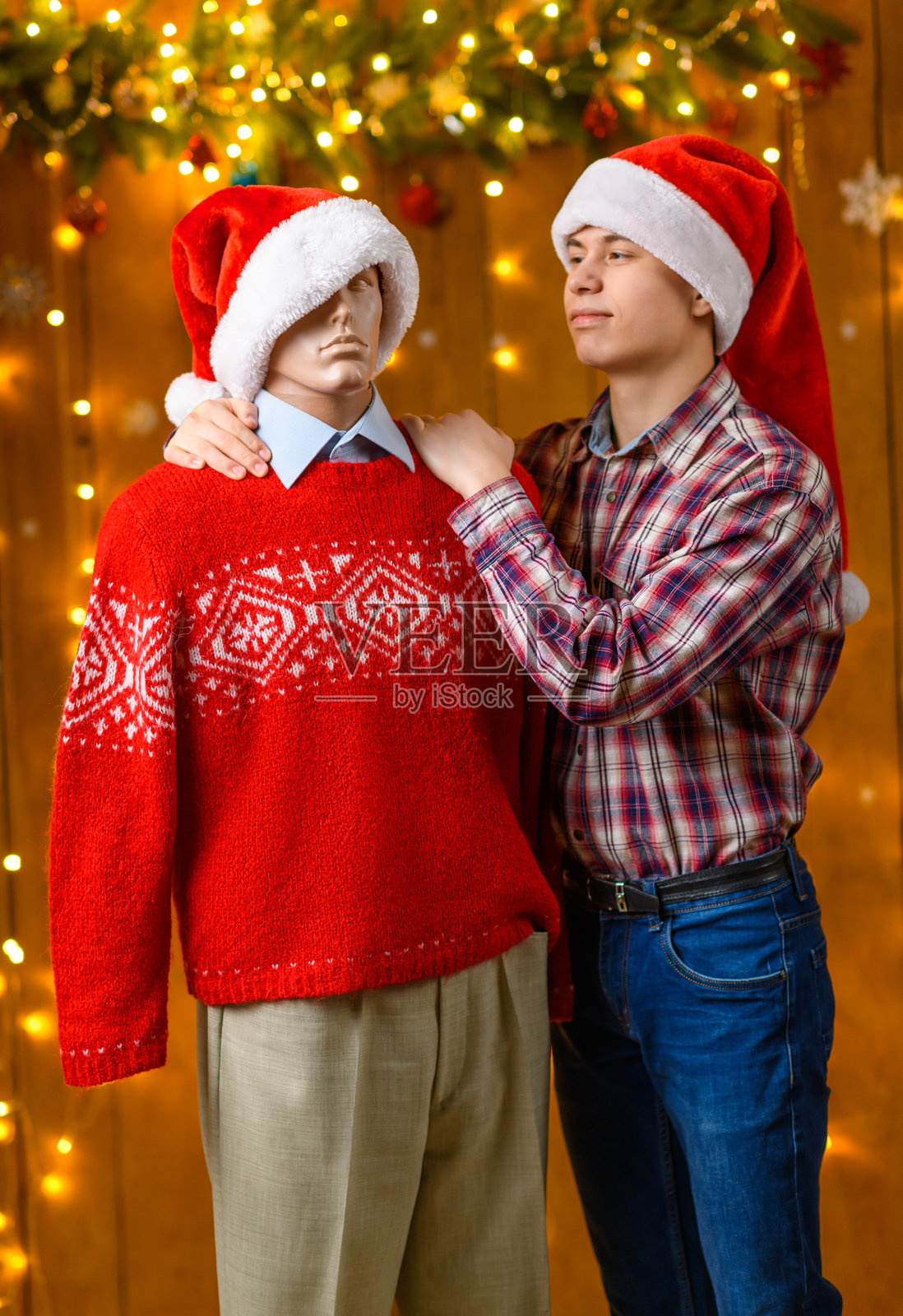 一个少年与男性人偶摆姿势，作为朋友，身边是新年装饰，节日灯光和花环，圣诞灯饰和装饰，节日主题。照片摄影图片