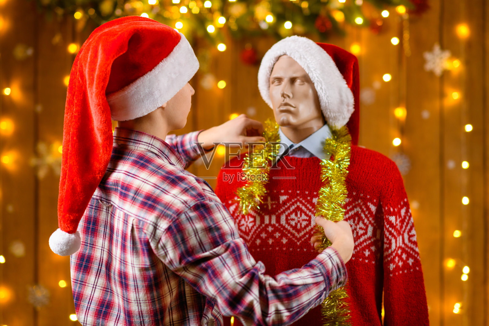 一个少年与男性人偶摆姿势，作为朋友，身旁是新年装饰，节日灯光和花环，圣诞灯饰和装饰，节日主题。照片摄影图片